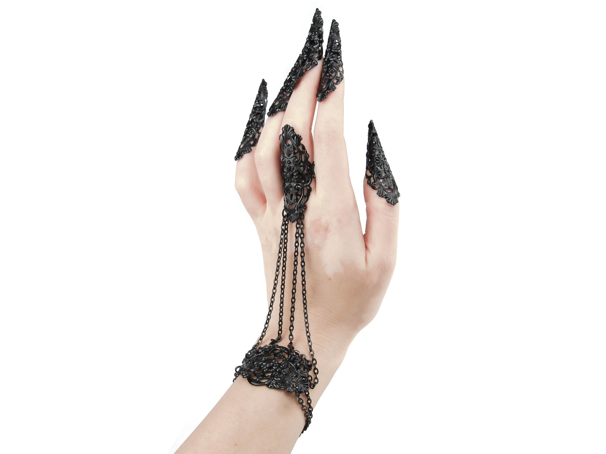 Experience the allure of gothic fashion with this luxurious silver hand chain adorned with black sharp nail claws. Its gothic-inspired design features intricate filigree metalwork on the hand, connected to a middle finger ring by elegant chains. Against a crisp white background, this meticulously crafted creation exudes refinement and mystery.