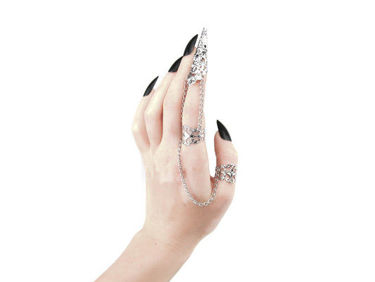 A hand elegantly displays Myril Jewels' double ring with a chain-connected claw, extending over the finger like a piece of wearable art. This silver piece, with intricate detailing, is a stunning example of neo-gothic design, perfect for adding a bold touch to gothic-chic, witchcore, or minimal goth attire. Ideal for Halloween, everyday fashion, or as a conversation starter at rave parties and festivals