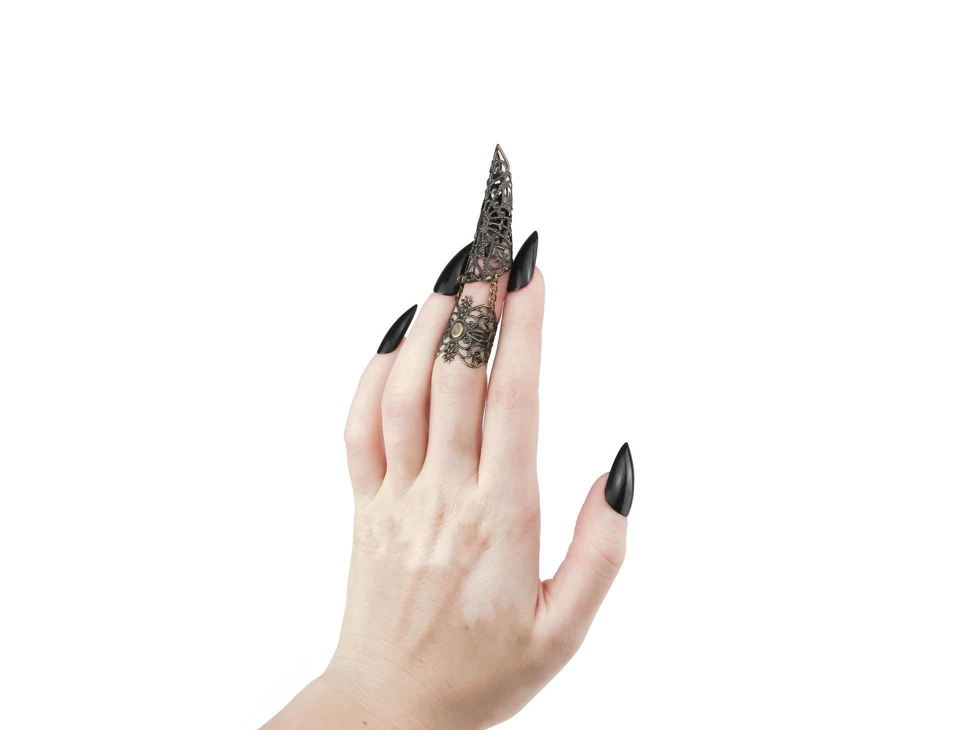 A hand with sleek black nails elegantly showcases a Myril Jewels claw ring on the middle finger, encapsulating the essence of neo-goth style. The ring's lace-like, intricate metalwork embodies dark-avantgarde fashion, making it a quintessential accessory for lovers of gothic and alternative aesthetics. Ideal for Halloween adornment, its punk jewelry vibe is subtle enough for everyday wear yet bold for the spotlight at rave parties and festivals. This piece is a striking representation of the gothic-chic