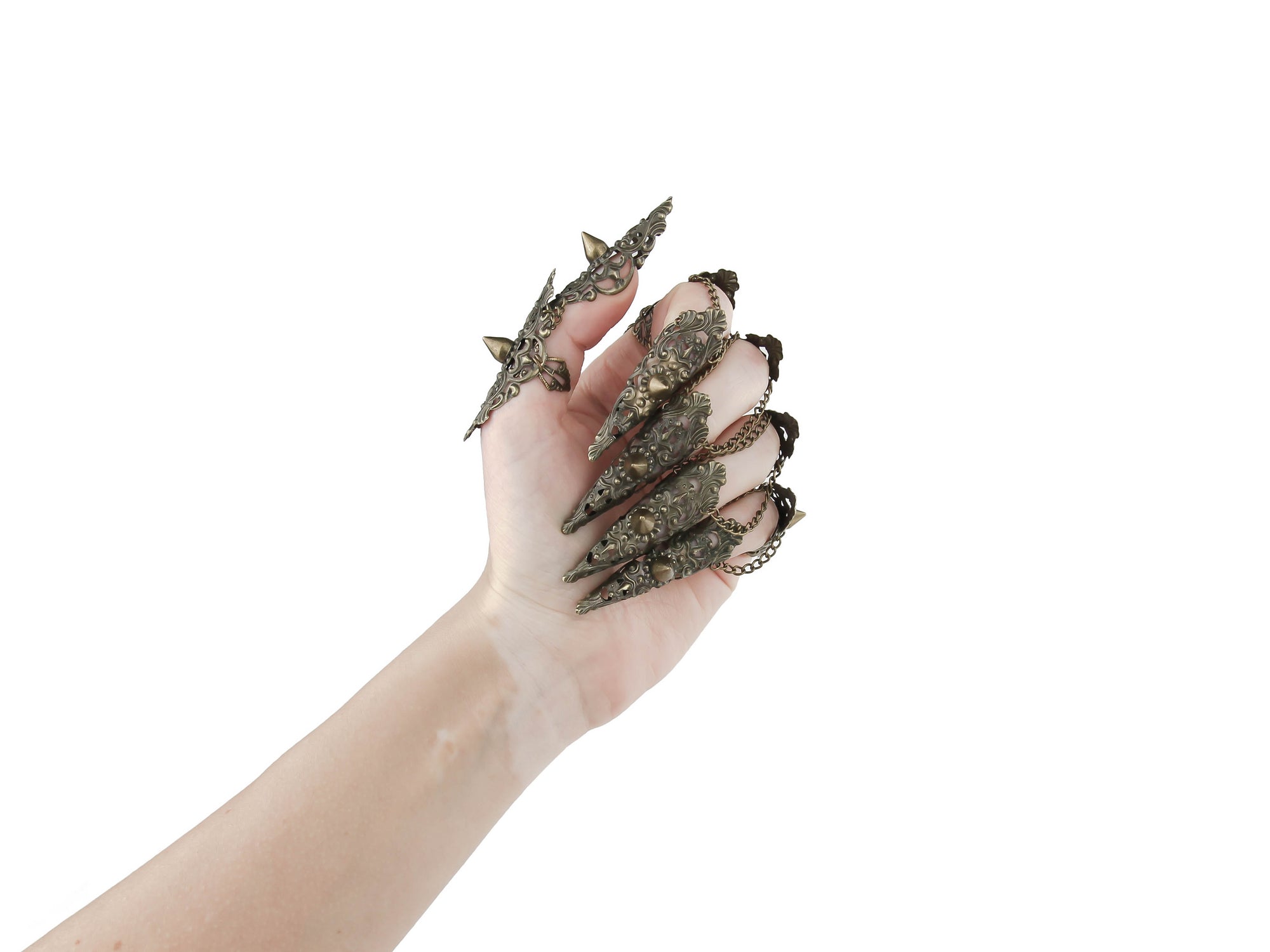 A hand is dramatically adorned with a full set of Myril Jewels studded nail claw rings in bronze. The claw rings feature elaborate filigree with pointed studs, invoking a bold neo-goth aesthetic. These edgy, dark-avantgarde pieces are perfect for those who embrace gothic and alternative styles, making them an ideal choice for Halloween, punk-inspired outfits, or as a statement addition to a whimsigoth or witchcore look. They also serve as eye-catching accessories for minimal goth everyday wear