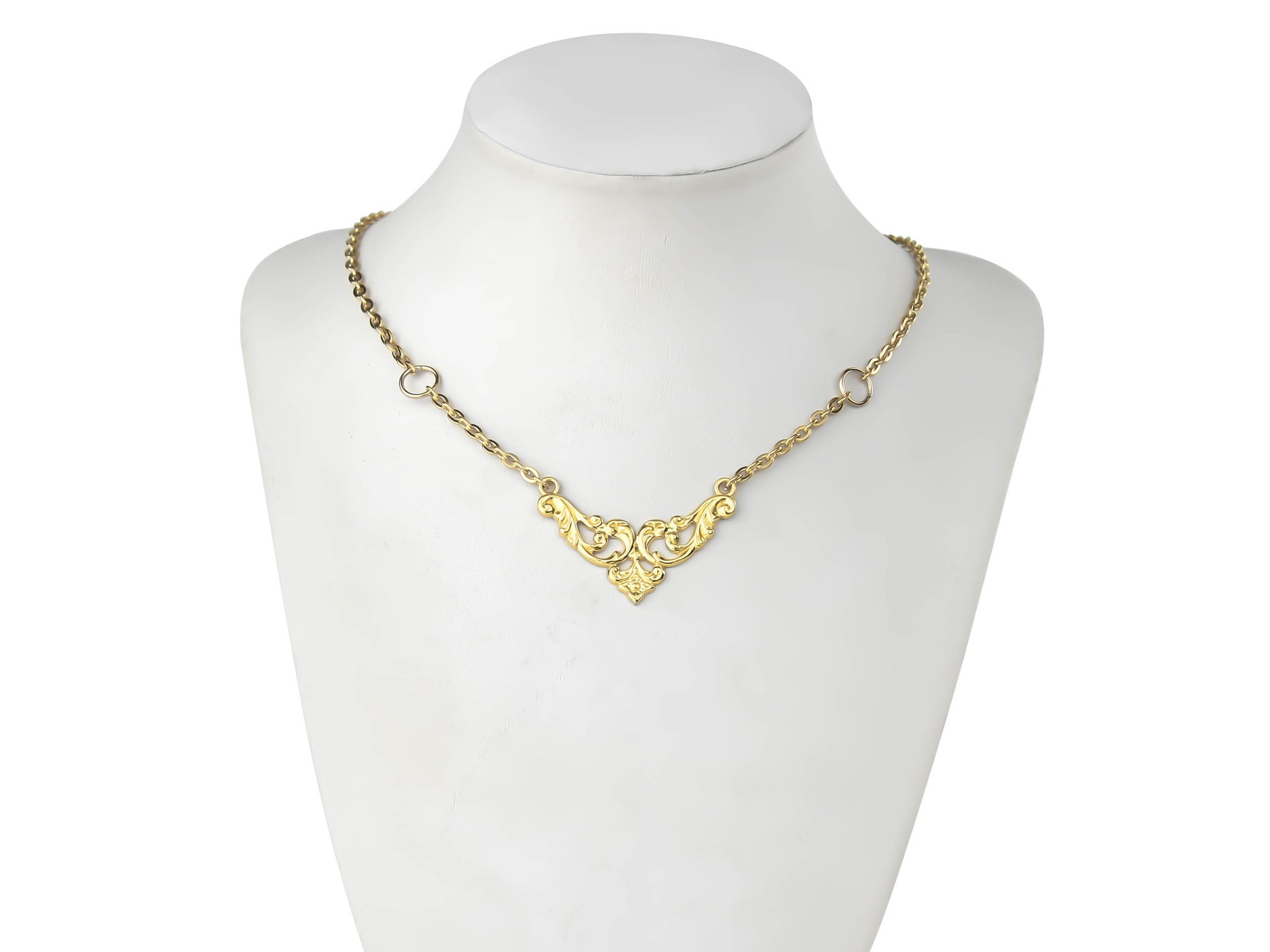 A gold gothic necklace from Myril Jewels drapes gracefully on a mannequin, featuring a delicate pendant with intricate, swirling filigree patterns. This elegant piece embodies the dark-avantgarde aesthetic, perfect for those who appreciate neo-gothic jewels, and is versatile enough for Halloween, whimsigoth fashion, or as a subtle touch to everyday gothic-chic attire