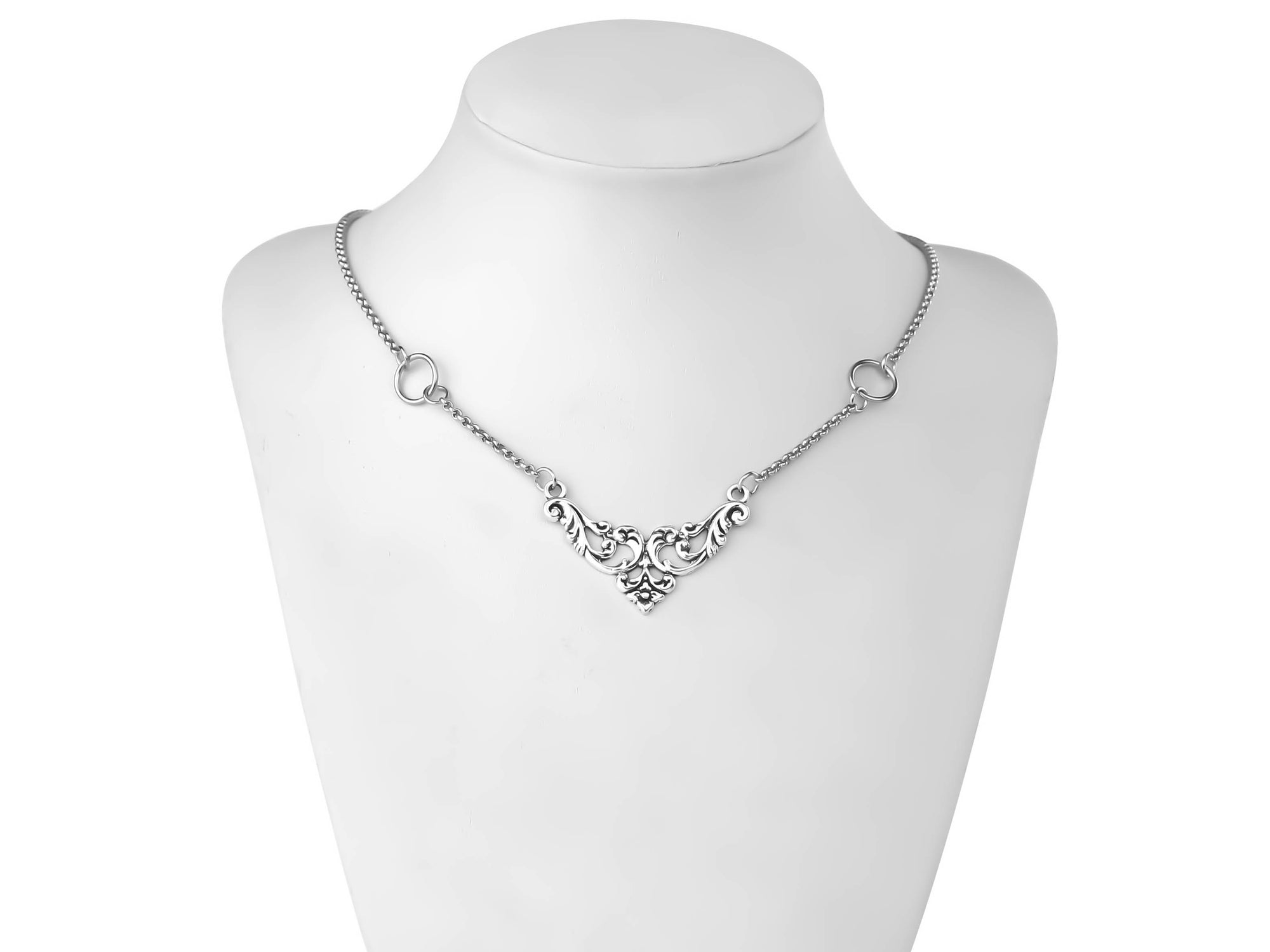 A delicate and elegant gothic necklace by Myril Jewels rests gracefully on a mannequin's neck, featuring ornate silver filigree that captures the essence of neo-gothic design. This necklace is a refined expression of dark-avantgarde fashion, ideal for those who appreciate a touch of gothic-chic in their everyday wear, or as a sophisticated accent to a whimsigoth or witchcore ensemble for festivals, rave parties, or Halloween events.