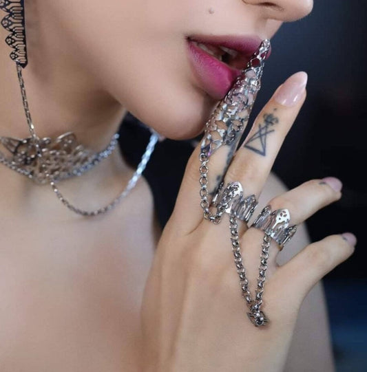 A striking close-up image showcases a model wearing a distinctive double ring from Myril Jewels, designed with claw features and a gothic arch pattern, embodying a dark-avantgarde aesthetic. This bold jewelry piece reflects a fusion of Halloween and punk influences, perfect for gothic-chic enthusiasts and a statement addition to festival or rave party attire. It serves as a unique goth girlfriend gift or a thoughtful friend gift idea, epitomizing everyday wear for those who favor a minimal goth style.