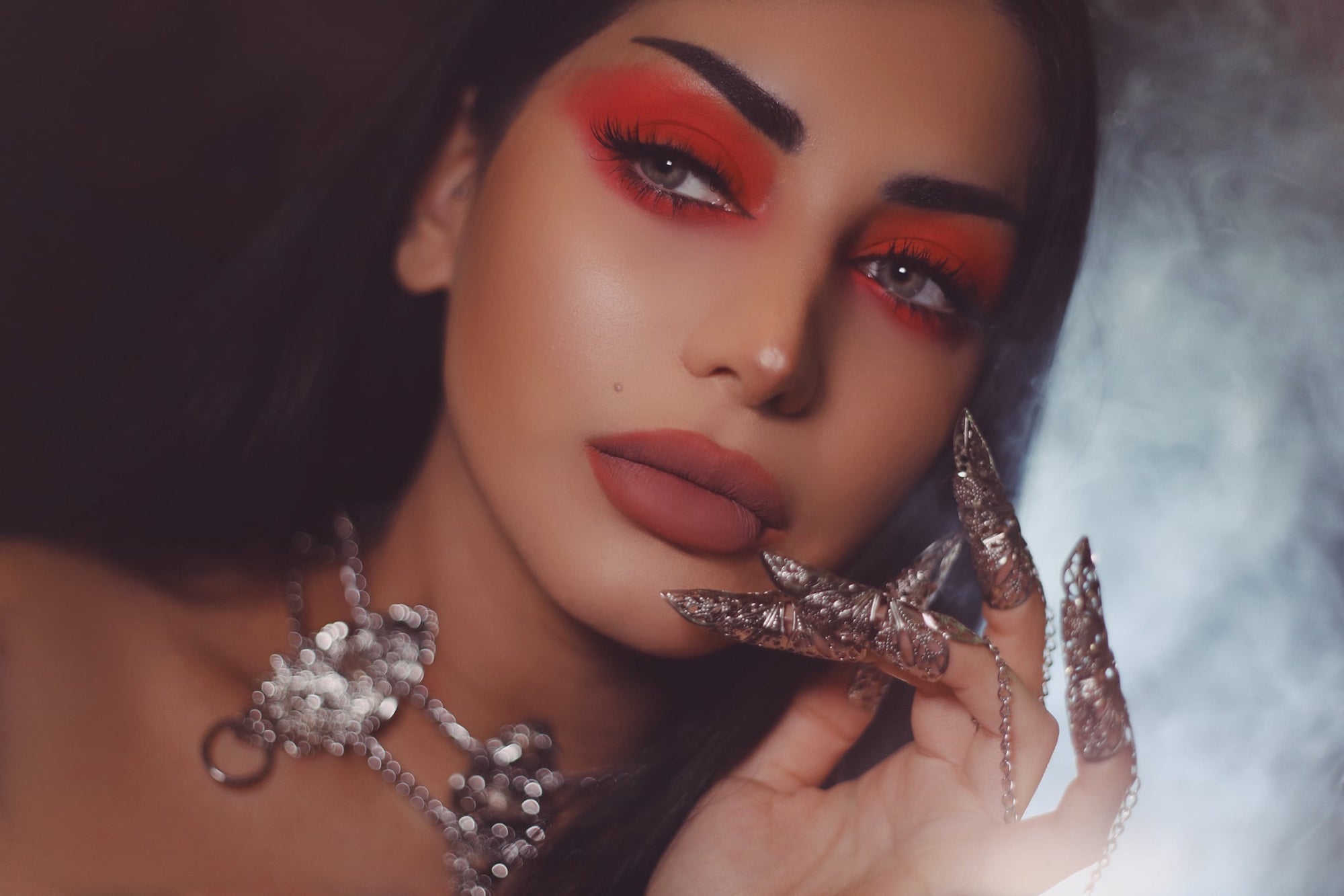 An alt model captivates with her gaze, adorned with a Myril Jewels punk studded metal choker, a masterpiece of dark avant-garde jewelry. The choker's detailed filigree complements her bold red eyeshadow, embodying a Neo Gothic aesthetic perfect for Halloween, Gothic Lolita, and Gothic-chic looks. This versatile piece exemplifies the whimsigoth and witchcore trends, suitable for everyday wear and enhancing a minimal goth style.