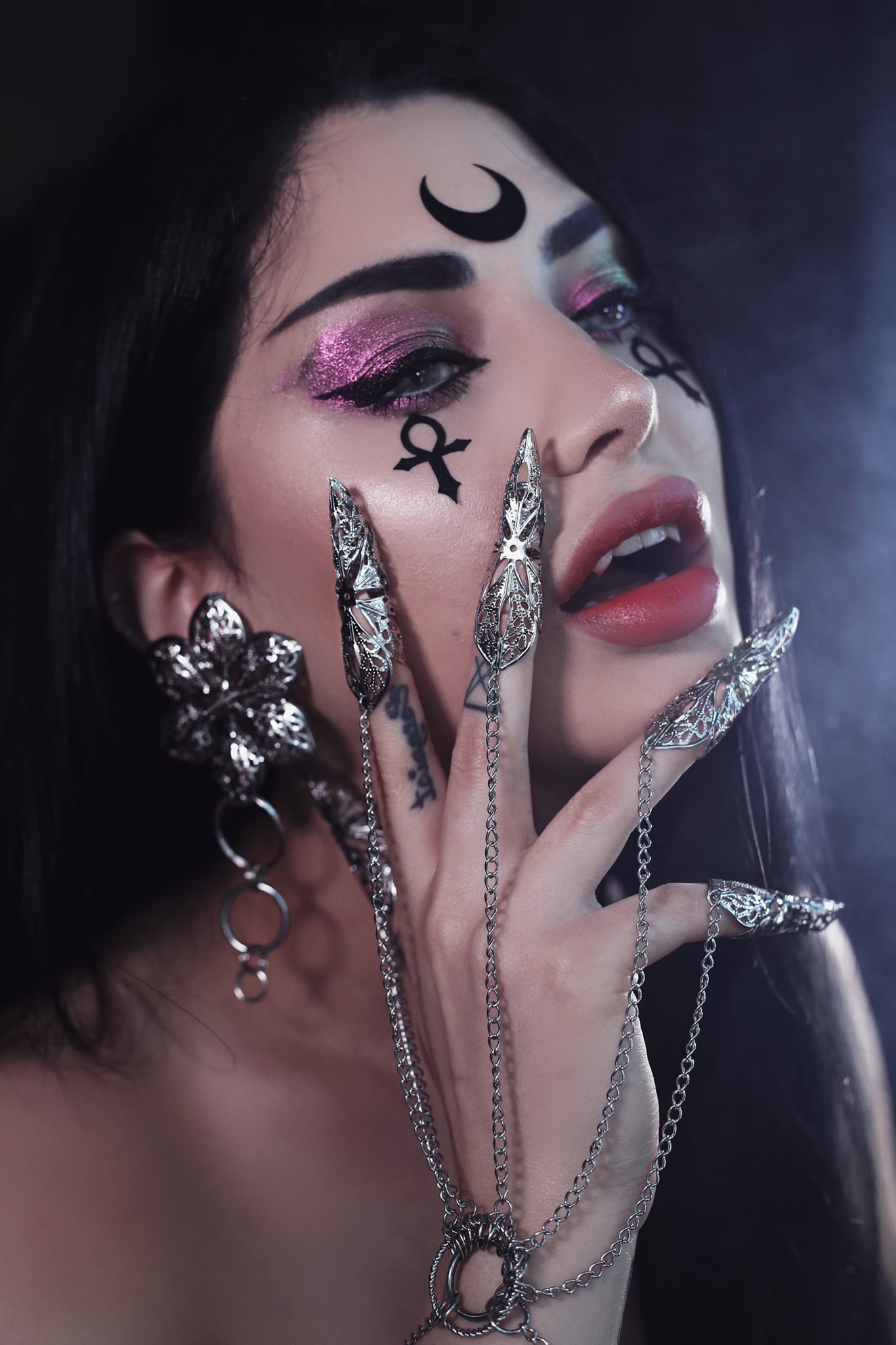 A captivating portrait featuring a model with bold makeup and symbolic tattoos, her hand adorned with a Myril Jewels hand chain bracelet with ornate claws. This neo-goth piece embodies the essence of Gothic-chic jewellery, perfect for Halloween and everyday wear by those who dare to stand out.