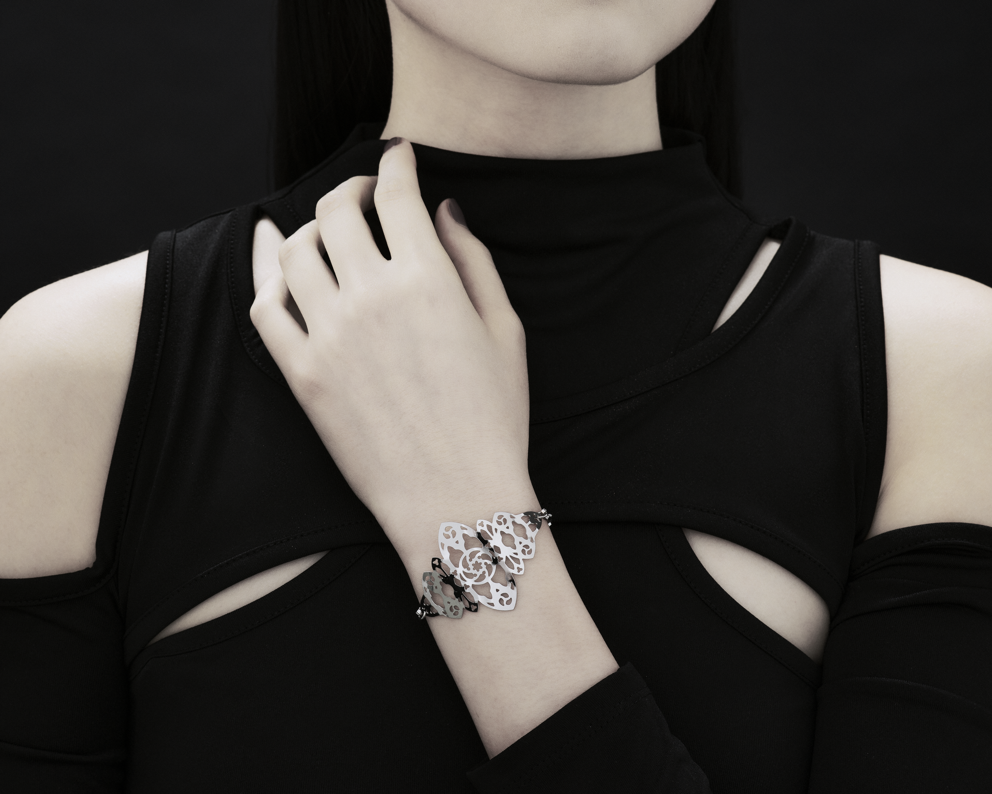  A model wears a Myril Jewels bracelet with intricate gothic architecture inspiration. The dark aesthetic of the bracelet contrasts elegantly with the model’s black attire, embodying the spirit of neo-goth jewelry. Perfect for those seeking a unique accessory for Halloween, everyday wear, or as a statement piece.