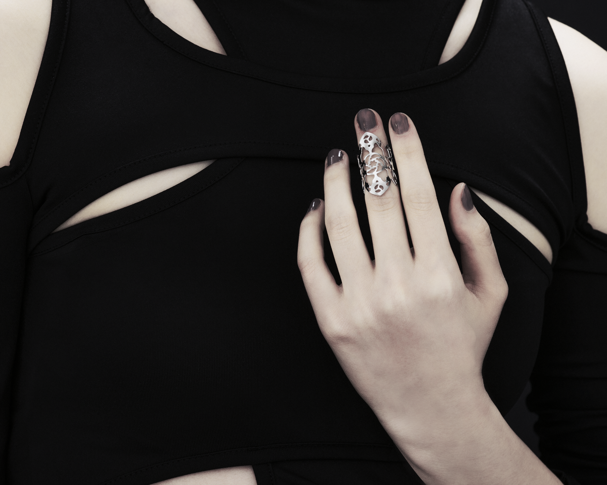 A hand adorned with a Myril Jewels gothic architecture inspired midi ring, set against a black sleeveless top with cut-out details. The ring’s intricate silver filigree design is reminiscent of the ornate complexity of gothic cathedrals, perfect for those who appreciate the dark-avantgarde, neo-goth aesthetic. This piece is a staple for gothic-chic fashion, a subtle nod to whimsigoth and witchcore styles, and an ideal accessory for Halloween, everyday wear