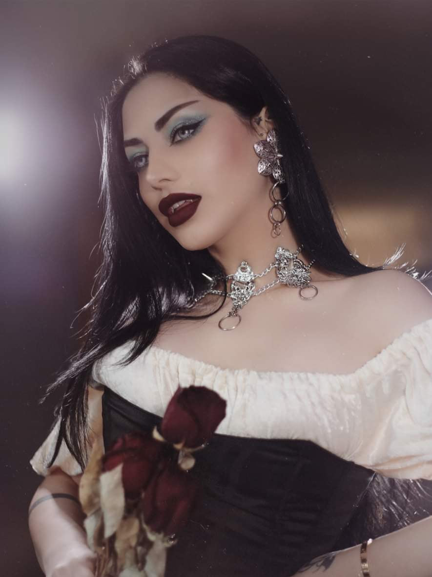 An alt model exudes dark sophistication in Myril Jewels' punk studded floral earrings and matching choker, embodying the spirit of Neo Gothic elegance. These handcrafted pieces, perfect for gothic and alternative fashion lovers, blend seamlessly with her dramatic makeup and the bouquet of dried roses she holds. Ideal for Halloween, gothic-chic events, or as a daring addition to any whimsigoth, witchcore, or minimal goth wardrobe