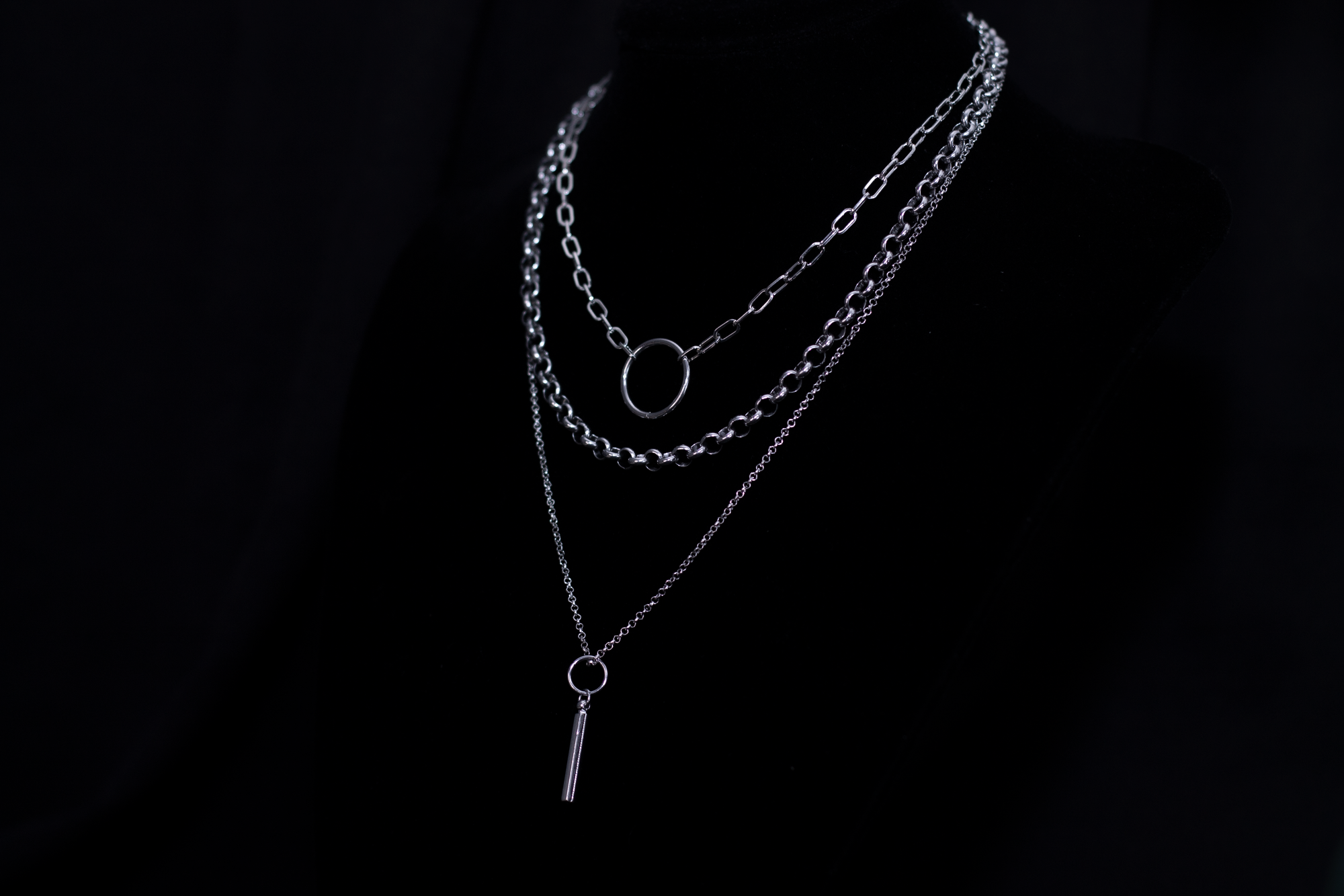 Showcasing a Myril Jewels punk multi-chain necklace with a layered design and a central hoop, this piece is a quintessential neo-goth accessory for an edgy, dark-avantgarde look.