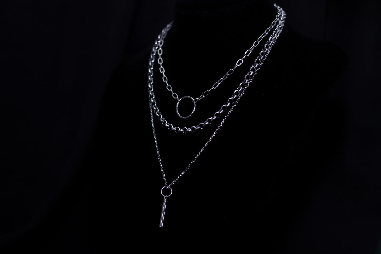 Showcasing a Myril Jewels punk multi-chain necklace with a layered design and a central hoop, this piece is a quintessential neo-goth accessory for an edgy, dark-avantgarde look.
