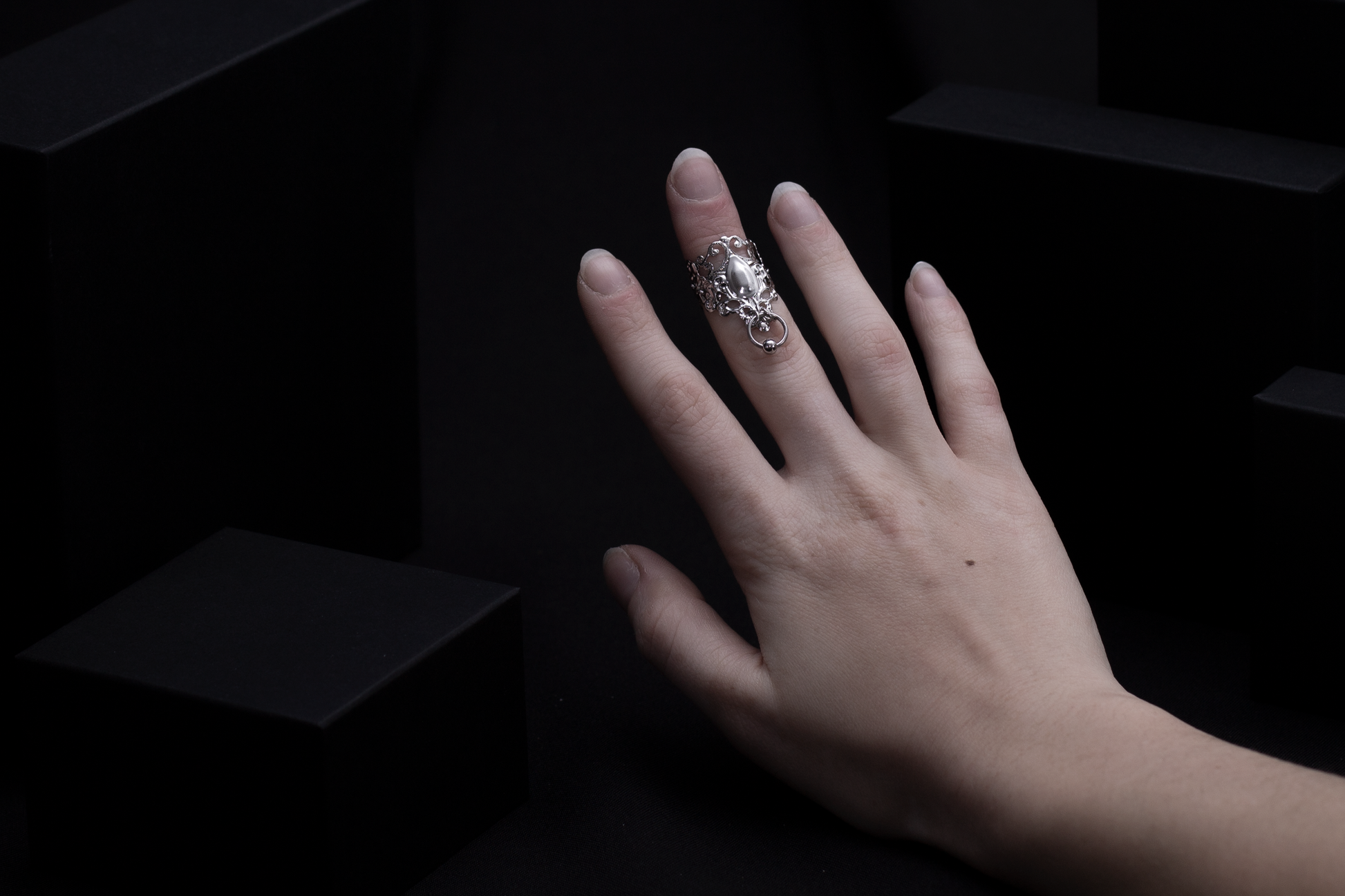 A hand models a Myril Jewels midi ring with neo-gothic allure, featuring ornate silver filigree and a central teardrop motif. This piece encapsulates gothic-chic and witchcore trends, making it an ideal accessory for bold everyday wear, rave events, or as an inspired goth girlfriend or friend gift.