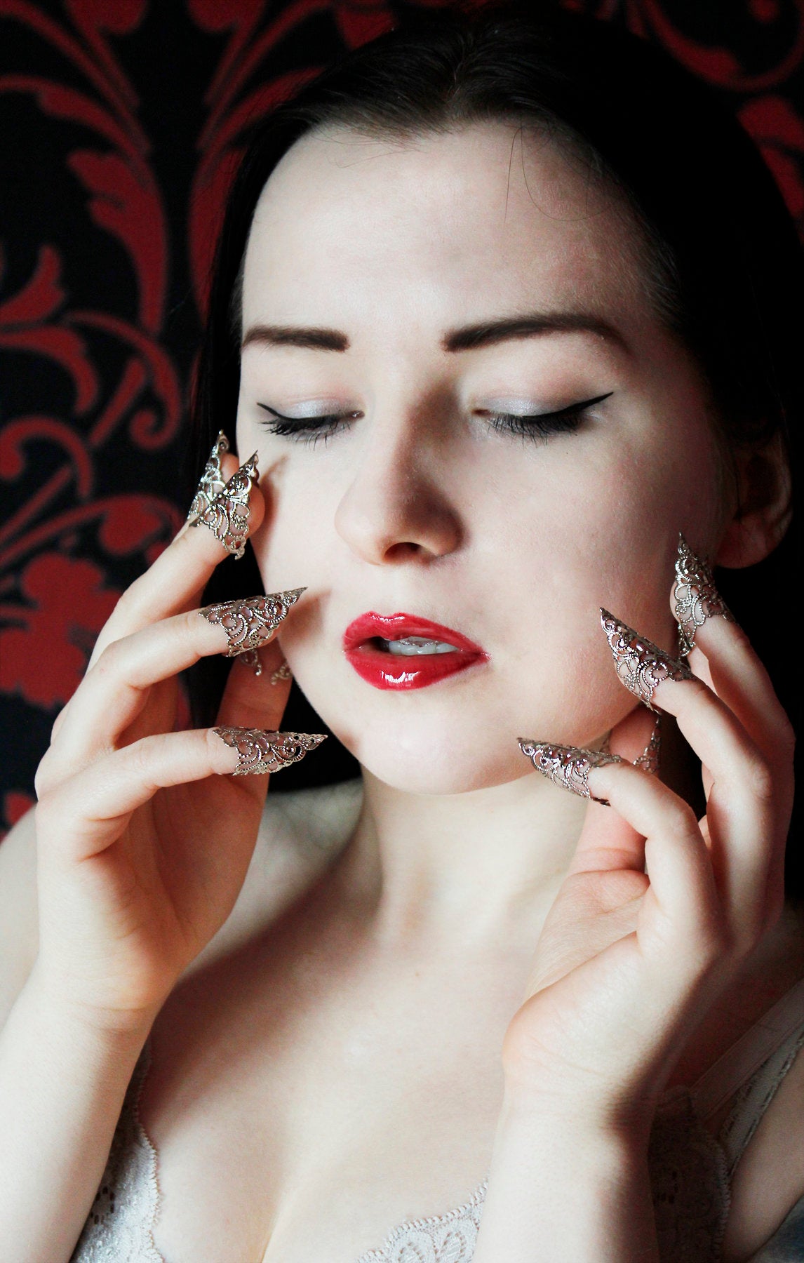 A serene portrait of a woman with closed eyes, her delicate features accentuated by Myril Jewels' goth nail rings. The silver filigree claws add a touch of neo-gothic charm, perfect for someone who cherishes Halloween and punk aesthetics, and values bold, whimsigoth jewelry as part of their everyday attire or for special events