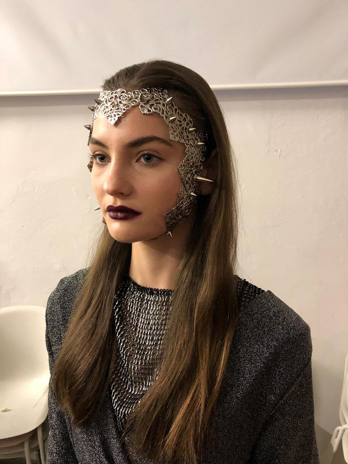  A model from Myril Jewels dons a punk filigree face frame mask, studded for an edgy look. This piece embodies the dark-avantgarde aesthetic, perfect for gothic and alternative style enthusiasts. Ideal for Halloween, festivals, or as a distinctive gift for a goth girlfriend.