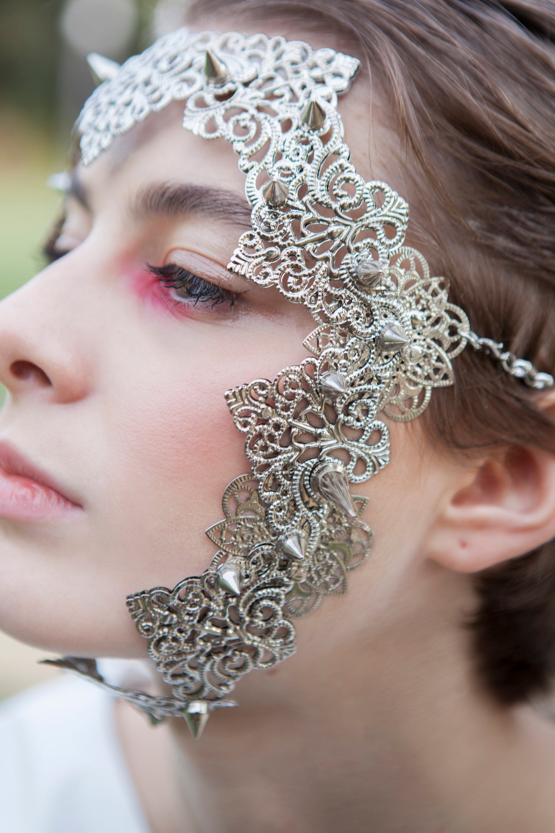  A close up shoot of a model showcases a stunning punk filigree face frame mask with studs, blending neo-goth elegance with a bold edge. Perfect for gothic and alternative style lovers, it's a statement piece for Halloween, festivals, or as a distinct goth girlfriend gift.
