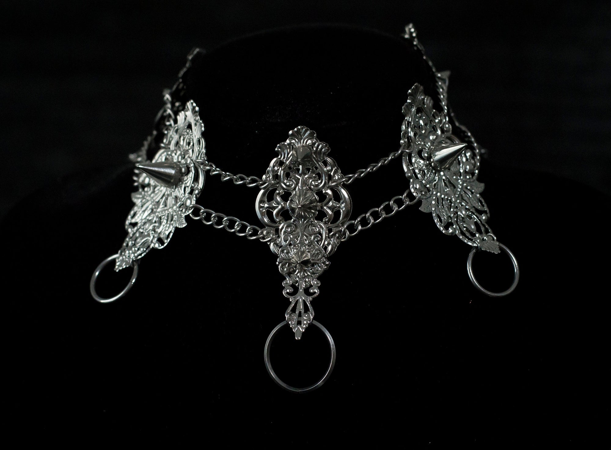 An exquisite Myril Jewels punk studded metal choker displayed on a dark backdrop, radiating gothic allure and alternative sophistication. This handcrafted Italian piece, with its intricate filigree and bold metal studs, is a true representation of Neo Gothic finesse. Ideal for those who gravitate towards Gothic Lolita, Gothic-chic, and whimsigoth aesthetics, it's a striking choice for Halloween jewelry collectors and embodies the witchcore vibe for everyday minimal goth fashion.