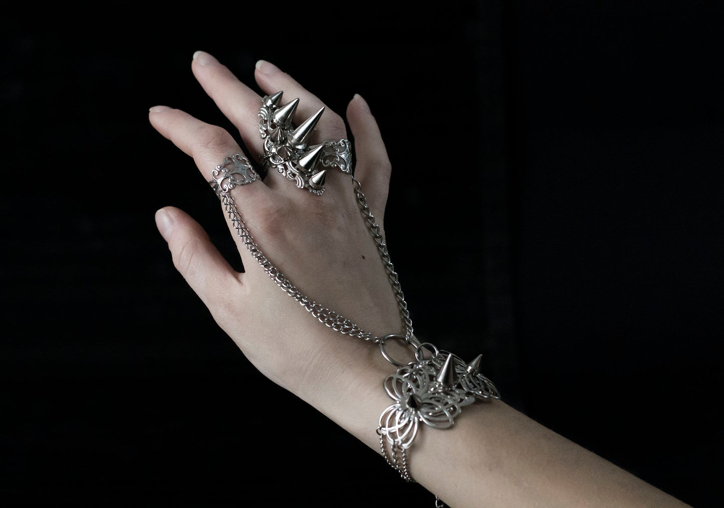 Capture the essence of punk rebellion with Myril Jewels' edgy studded ring and matching hand chain bracelet ring. These bold statement pieces, with its sharp studs and metallic finish, are a must-have for lovers of dark-avantgarde and gothic accessories. Ideal for Halloween, it also complements everyday minimal goth looks, Witchcore styles, and Gothic-chic ensembles, offering a versatile addition to any Neo Gothic jewel collection