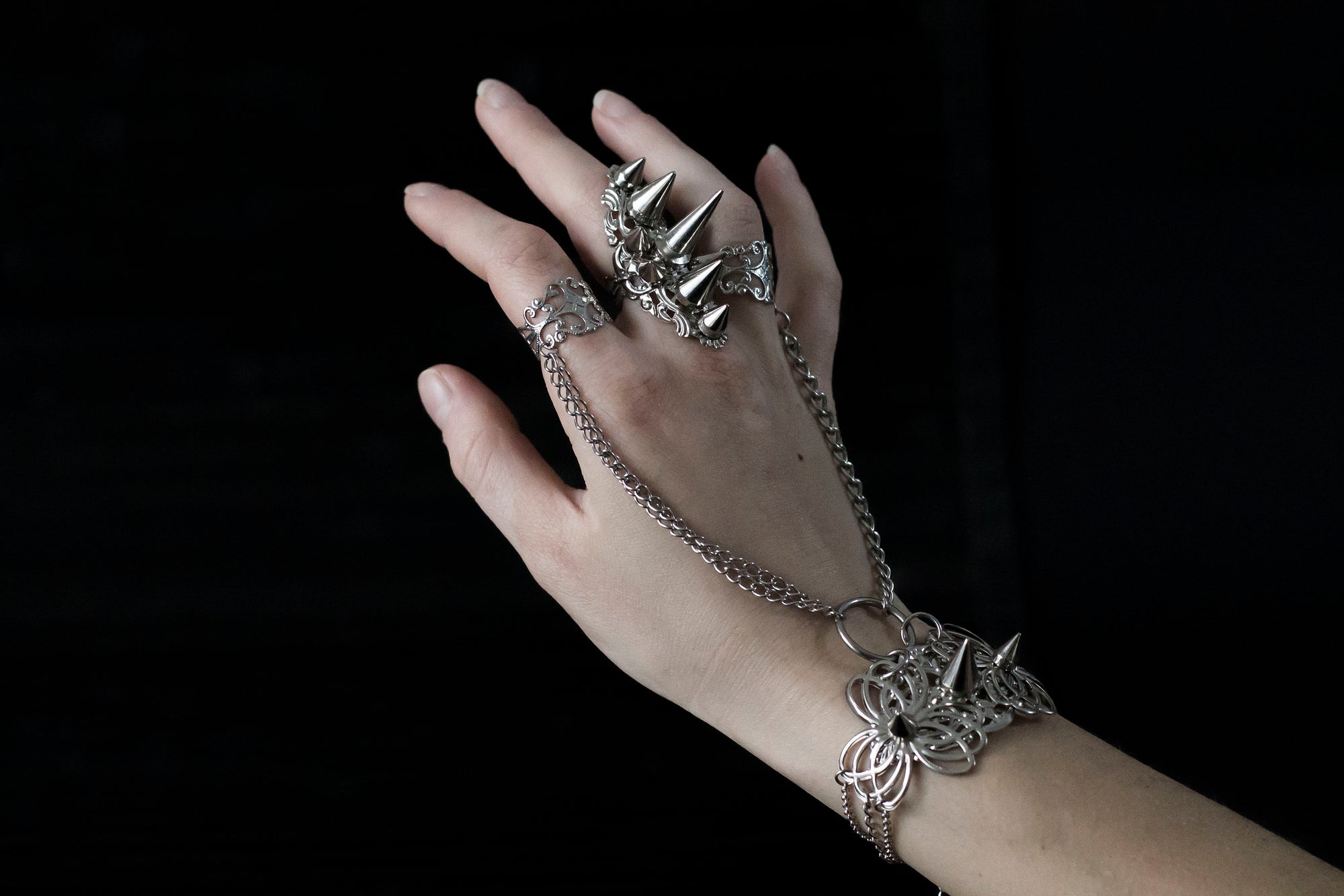 Capture the essence of punk rebellion with Myril Jewels' edgy studded ring and matching hand chain bracelet ring. These bold statement pieces, with its sharp studs and metallic finish, are a must-have for lovers of dark-avantgarde and gothic accessories. Ideal for Halloween, it also complements everyday minimal goth looks, Witchcore styles, and Gothic-chic ensembles, offering a versatile addition to any Neo Gothic jewel collection