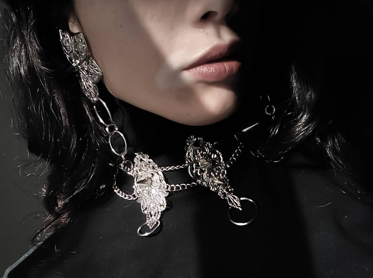 A close-up image captures the essence of Myril Jewels' craftsmanship with a punk studded metal choker adorned by an alternative model. The intricate design and studded detailing reflect a Neo Gothic influence, making it a coveted piece for those who appreciate Halloween jewelry, punk style, and Gothic-chic trends. The choker's bold presence is perfect for Whimsigoth and Witchcore enthusiasts or as a distinct touch to minimal goth daily wear