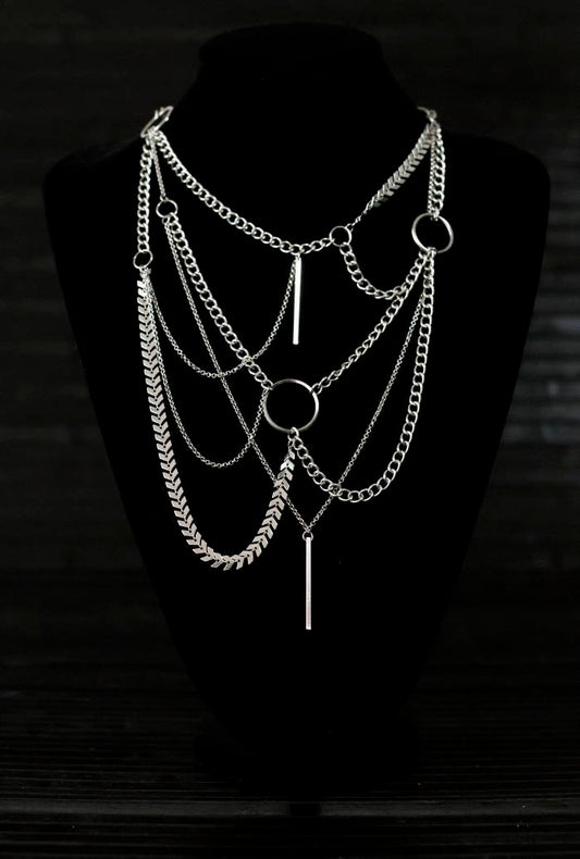 A multi-layered Myril Jewels necklace, featuring mixed chains and central o-rings, embodies neo-gothic elegance. Ideal for Halloween, festivals, or as a bold statement piece, this necklace is perfect for the goth-chic aesthetic and makes a thoughtful gift for those embracing a dark-avantgarde style.