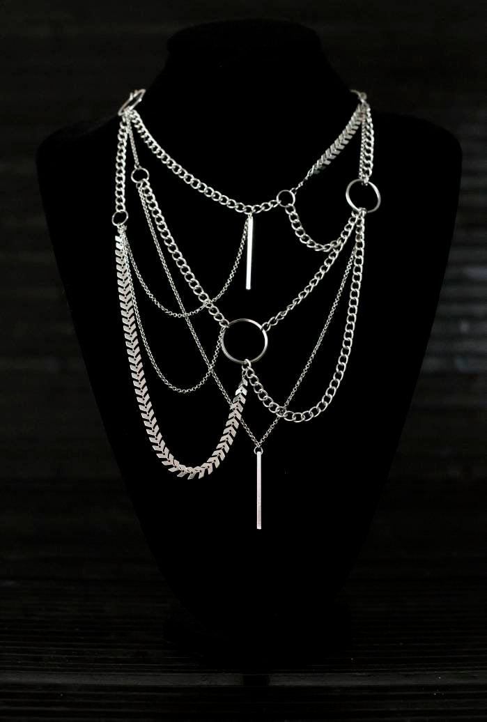 Multi-layered Myril Jewels necklace, showcasing a neo-goth aesthetic with an array of chains and an o-ring, perfect for a bold gothic-chic statement. Ideal for Halloween, rave parties, or as an everyday wear piece for those who embrace a dark avant-garde style.