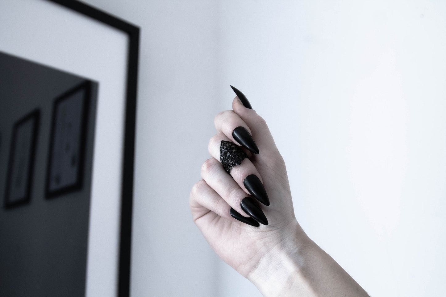  A hand with long stiletto black nails is wearing an intricately designed Myril Jewels gothic midi ring, showcasing neo-gothic finesse. Ideal for Witchcore and whimsigoth enthusiasts, perfect as a bold yet elegant Halloween accessory or a unique goth girlfriend gift.