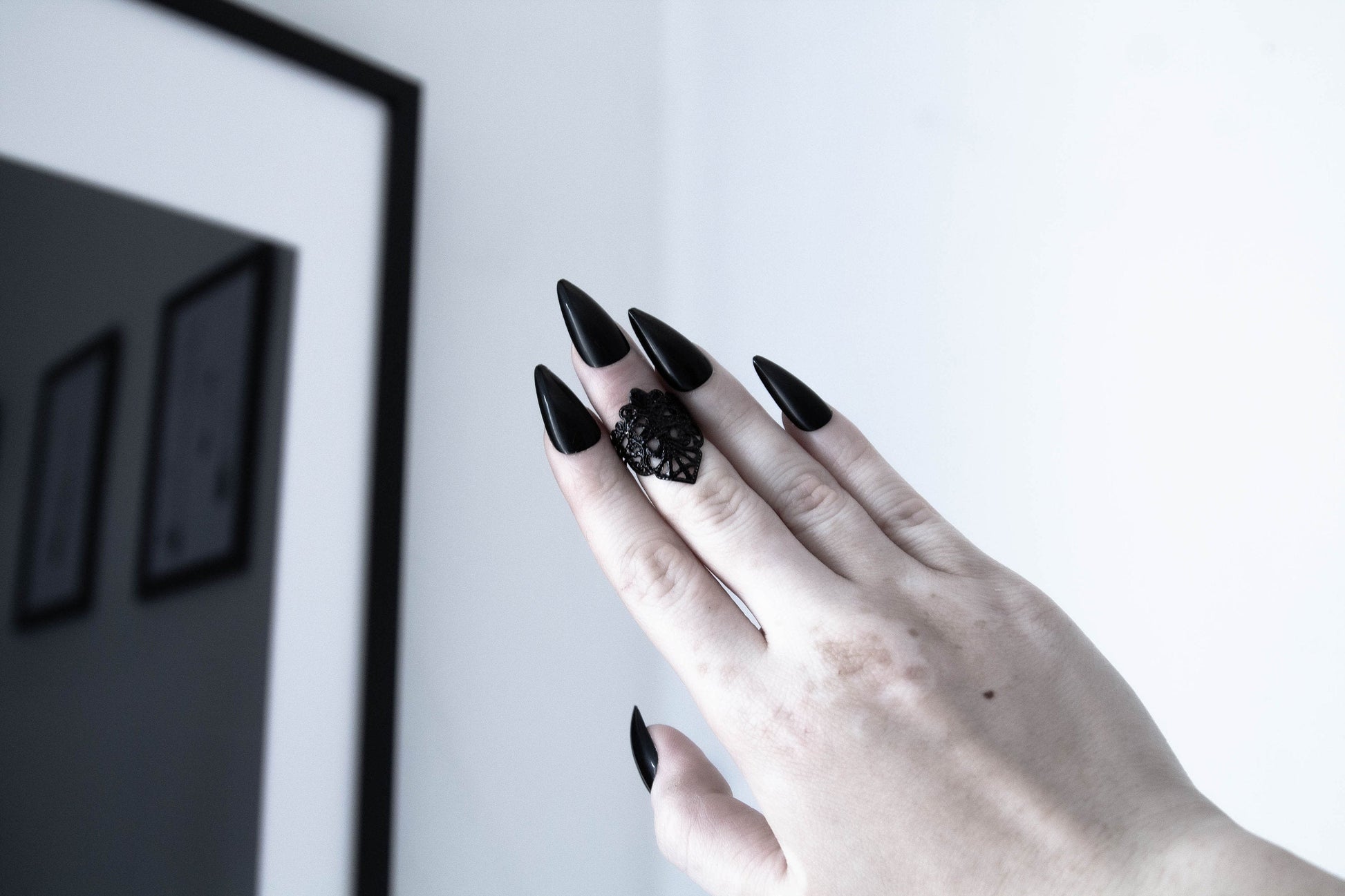  A hand with long stiletto black nails is wearing an intricately designed Myril Jewels gothic midi ring, showcasing neo-gothic finesse. Ideal for Witchcore and whimsigoth enthusiasts, perfect as a bold yet elegant Halloween accessory or a unique goth girlfriend gift.