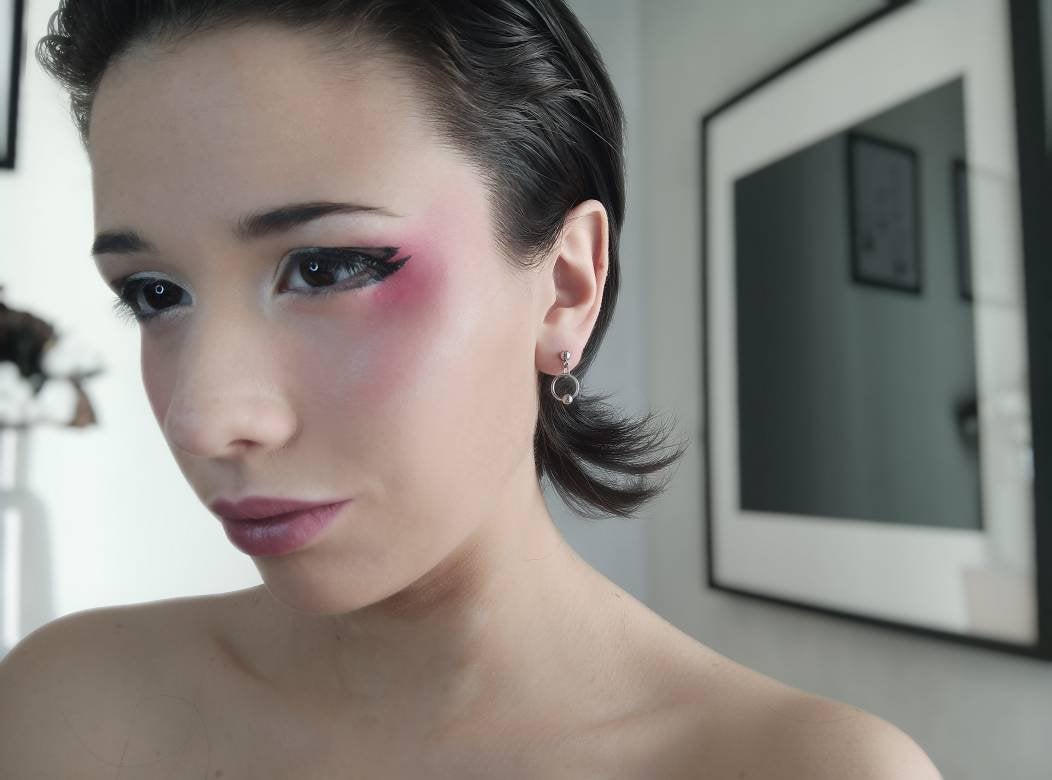 A poised model showcases mini hoop earrings from Myril Jewels, complementing a neo-gothic style. The earrings, perfect for gothic and alternative fashion enthusiasts, add a subtle yet edgy touch to everyday wear. They reflect Myril Jewels' dedication to creating dark, avant-garde pieces that resonate with the aesthetic of Halloween, Witchcore, and minimal goth. These earrings are ideal for those seeking a touch of punk elegance or a distinctive festival jewelry piece.