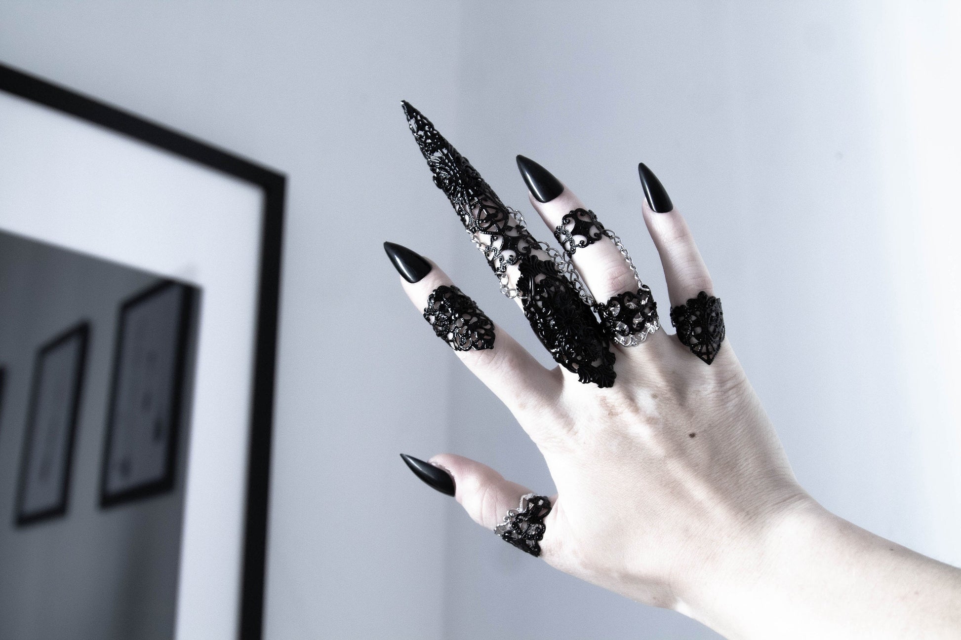 A hand adorned with Myril Jewels' neo-goth rings, showcasing diverse, intricate designs. Each piece embodies a dark-avantgarde aesthetic, perfect for Halloween, daily wear, or as a bold festival statement. Ideal gifts for the gothic-chic lover or to elevate a drag queen's ensemble.