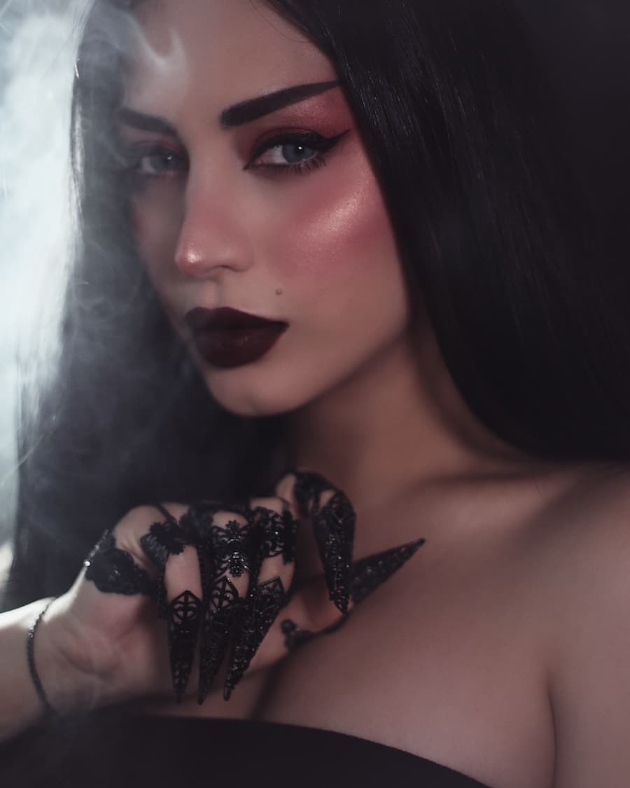 "A smoky aura surrounds a model whose intense gaze and dark makeup are heightened by Myril Jewels' full hand silver metal glove with lace-like claw rings. The neo-gothic jewelry, set against her alluring look, perfectly captures the essence of dark avant-garde, suitable for gothic and alternative style connoisseurs.
