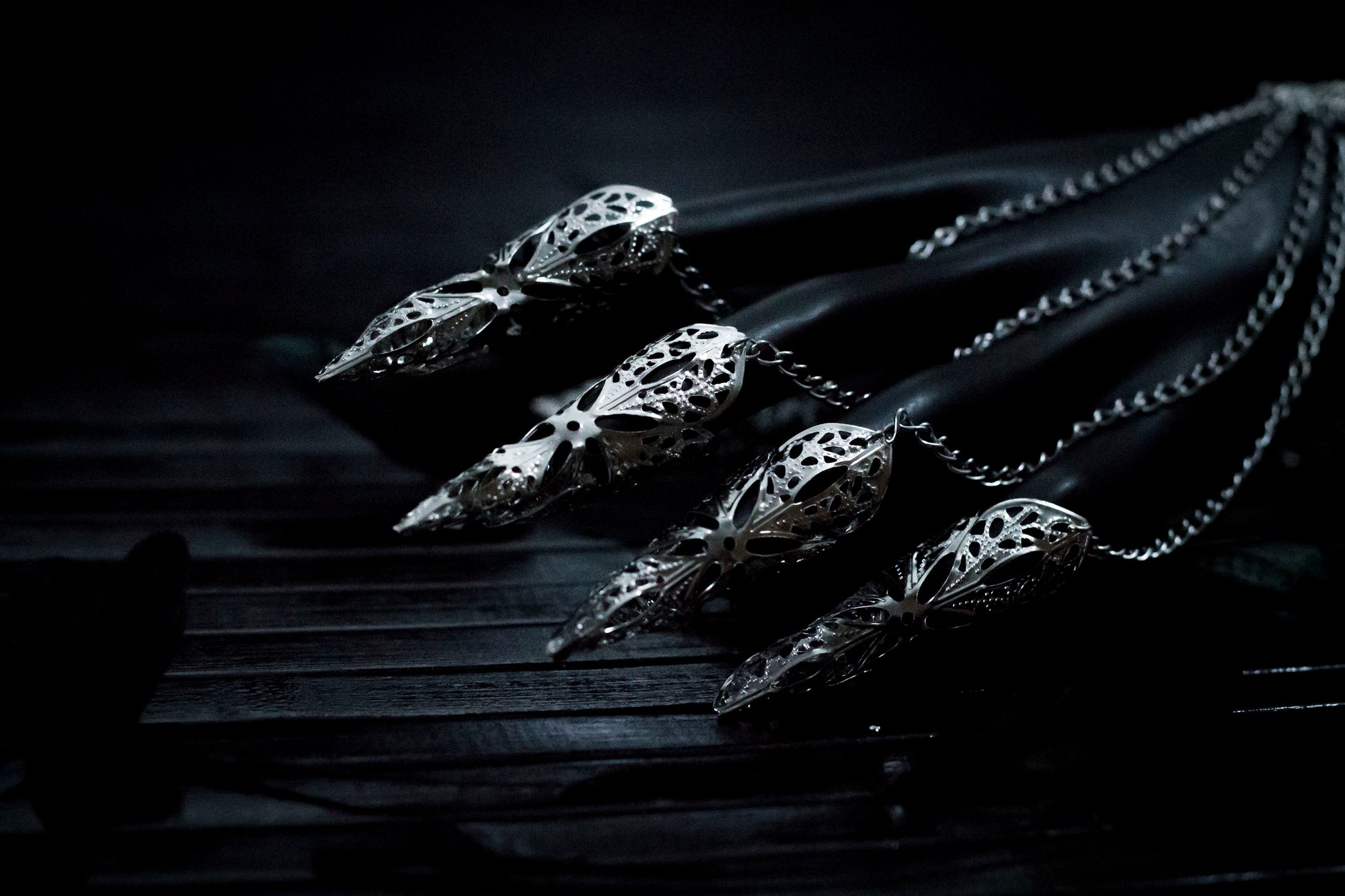 A close up shoot of a hand that extends dramatically with Myril Jewels' hand chain bracelet, each finger tipped with a delicate claw ring. The jewelry's silver filigree work captures the dark, neo-gothic aesthetic, perfect for adding a bold touch to Halloween looks or as a statement piece for those who favor gothic-chic or witchcore styles.