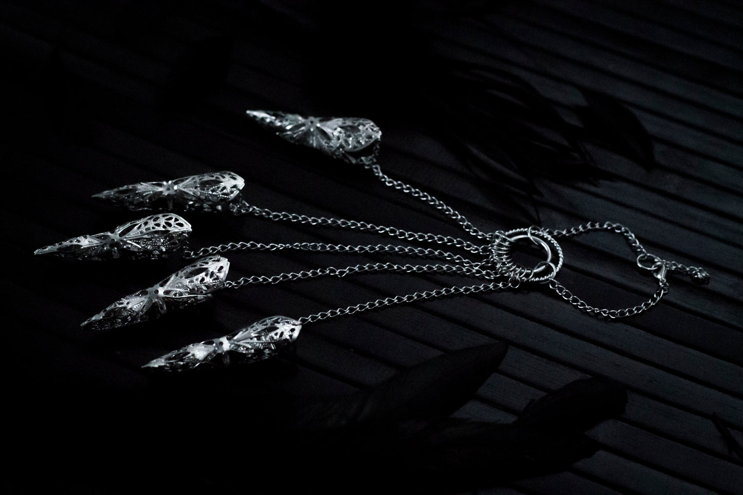 A close up shoot of a hand that extends dramatically with Myril Jewels' hand chain bracelet, each finger tipped with a delicate claw ring. The jewelry's silver filigree work captures the dark, neo-gothic aesthetic, perfect for adding a bold touch to Halloween looks or as a statement piece for those who favor gothic-chic or witchcore styles.