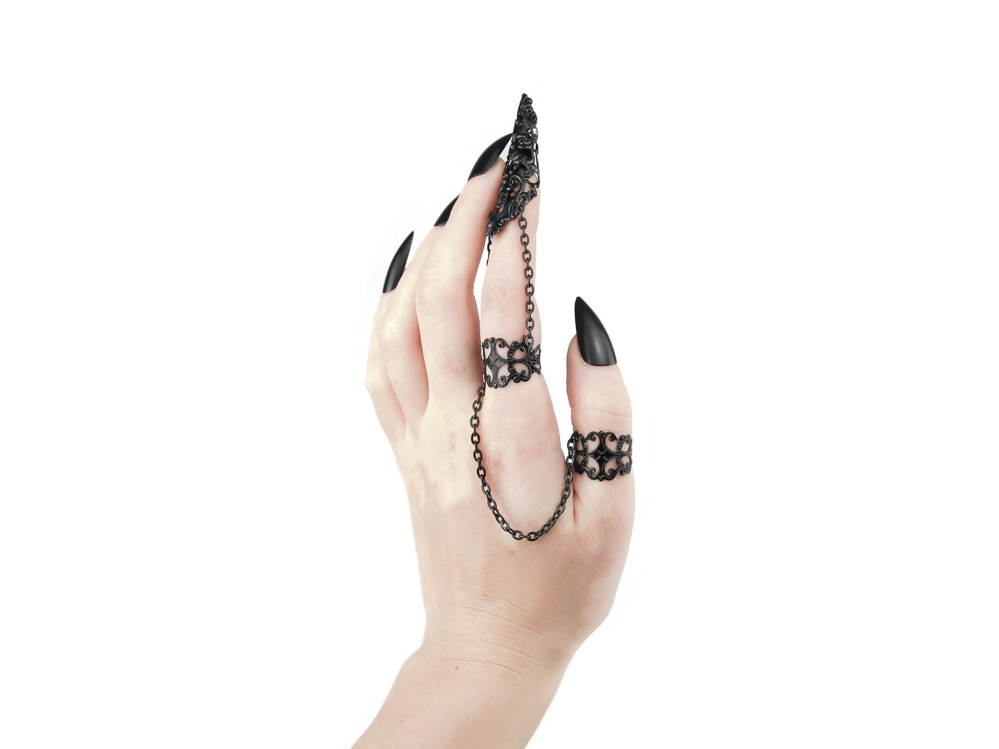 A striking hand showcases a Myril Jewels double ring extending into a dramatic claw over the finger, intricately designed with a black filigree pattern. This bold piece is an emblem of neo-goth style, perfect for those who favor dark-avantgarde jewelry. Ideal for Halloween, it complements a punk look, and adds an edge to minimal goth, everyday wear, or as a conversation piece at rave parties and festivals