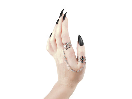 A graceful hand with sharp black nails showcases Myril Jewels' gothic-chic rings, connected by a delicate chain. The intricate, silver filigree design is perfect for gothic lolita, punk, and neo-gothic enthusiasts, making these rings a must-have for any dark-avantgarde accessory collection, especially for Halloween or witchcore fashion statements.