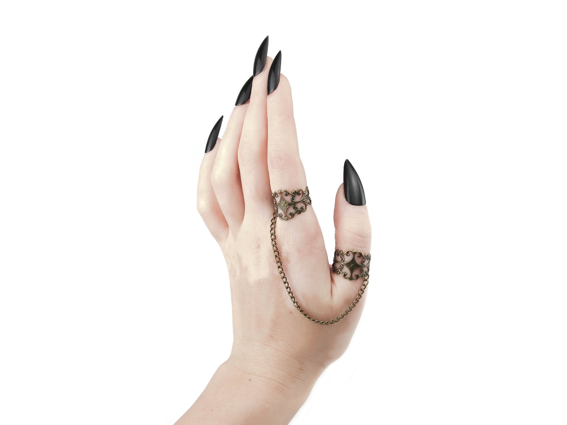 A slender hand with sharp, black nails elegantly showcases Myril Jewels' gothic-chic rings in bronze, connected by a delicate chain, epitomizing dark-avantgarde jewelry. Ideal for punk, neo-gothic, and witchcore enthusiasts, these rings are a must-have accessory for any Halloween or whimsigoth-inspired outfit.
