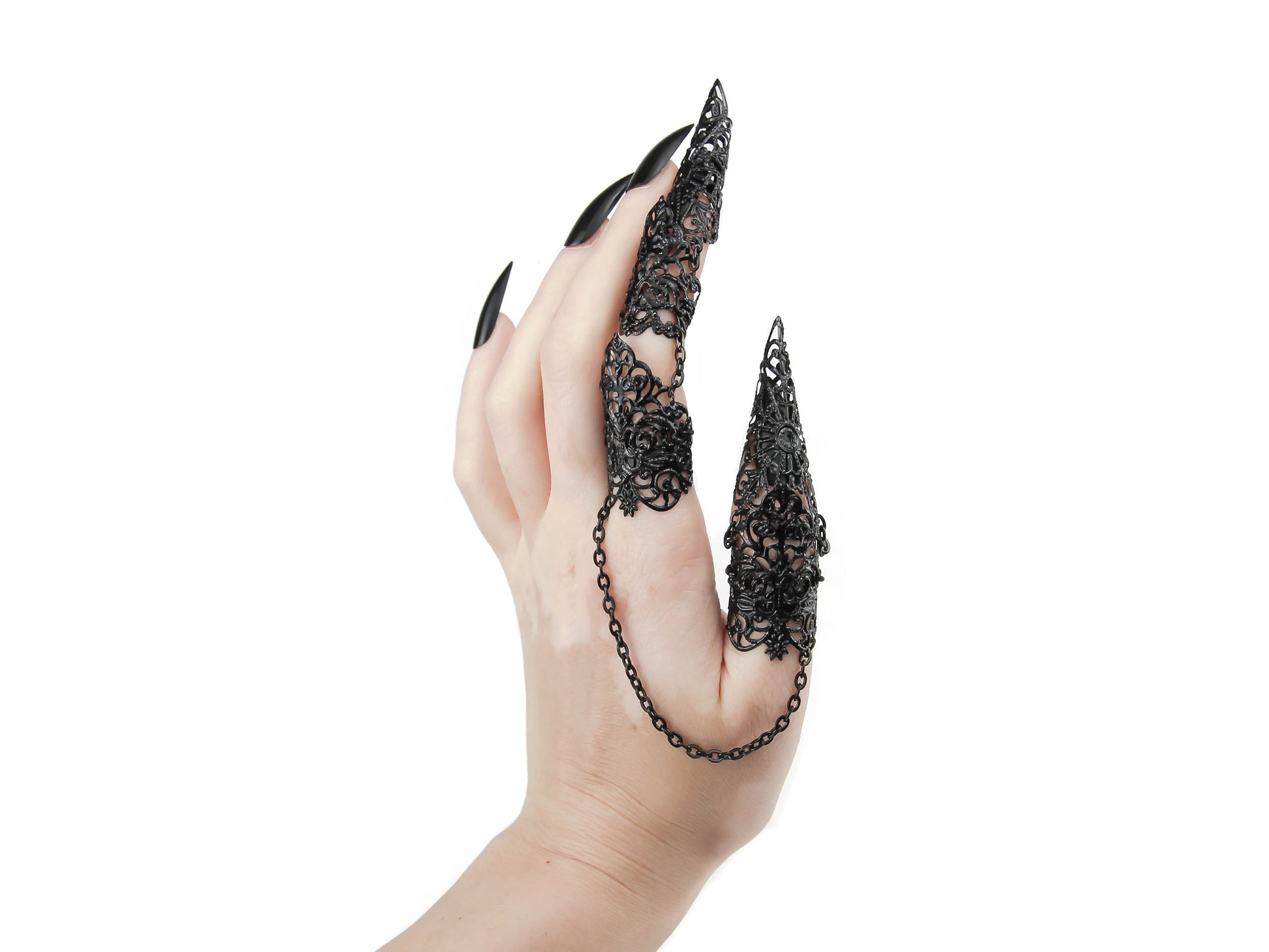 A hand adorned with Myril Jewels' distinctive gothic full finger double rings, featuring elaborate claw-like extensions that cover the fingertips. The rings, connected by a fine chain, showcase intricate black filigree work, reflecting a dark, avant-garde aesthetic. This bold accessory is a statement piece for gothic, punk, and neo-gothic jewelry collectors, ideal for Halloween, witchcore fashion, or as an eye-catching element for everyday wear and festival outfits.