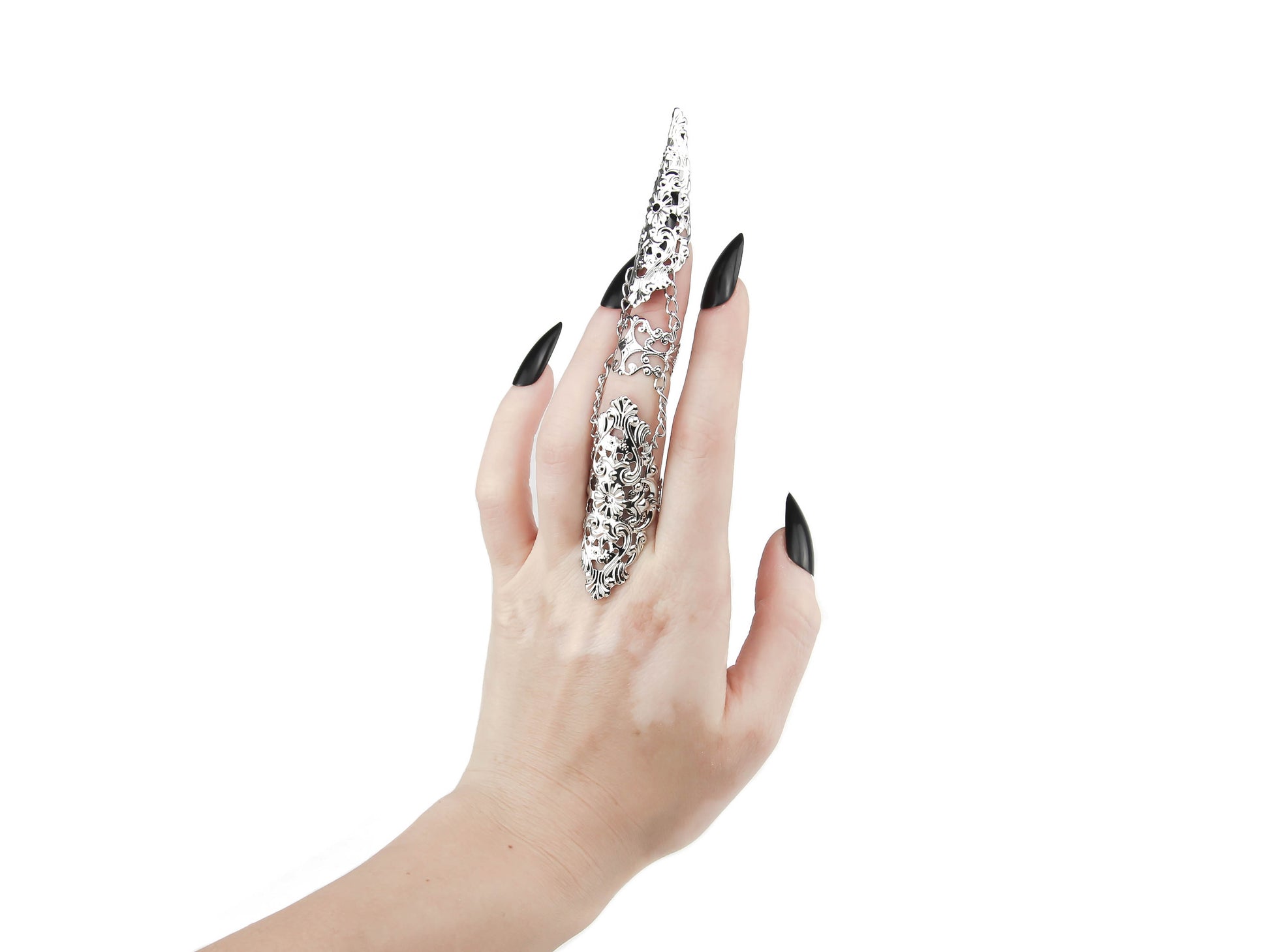 A hand models on the middle finger a striking Myril Jewels articulated finger armor ring, with polished silver filigree detailing perfect for dark-avantgarde and gothic fashion enthusiasts. This Italian-made, handcrafted piece captures the essence of alternative luxury.