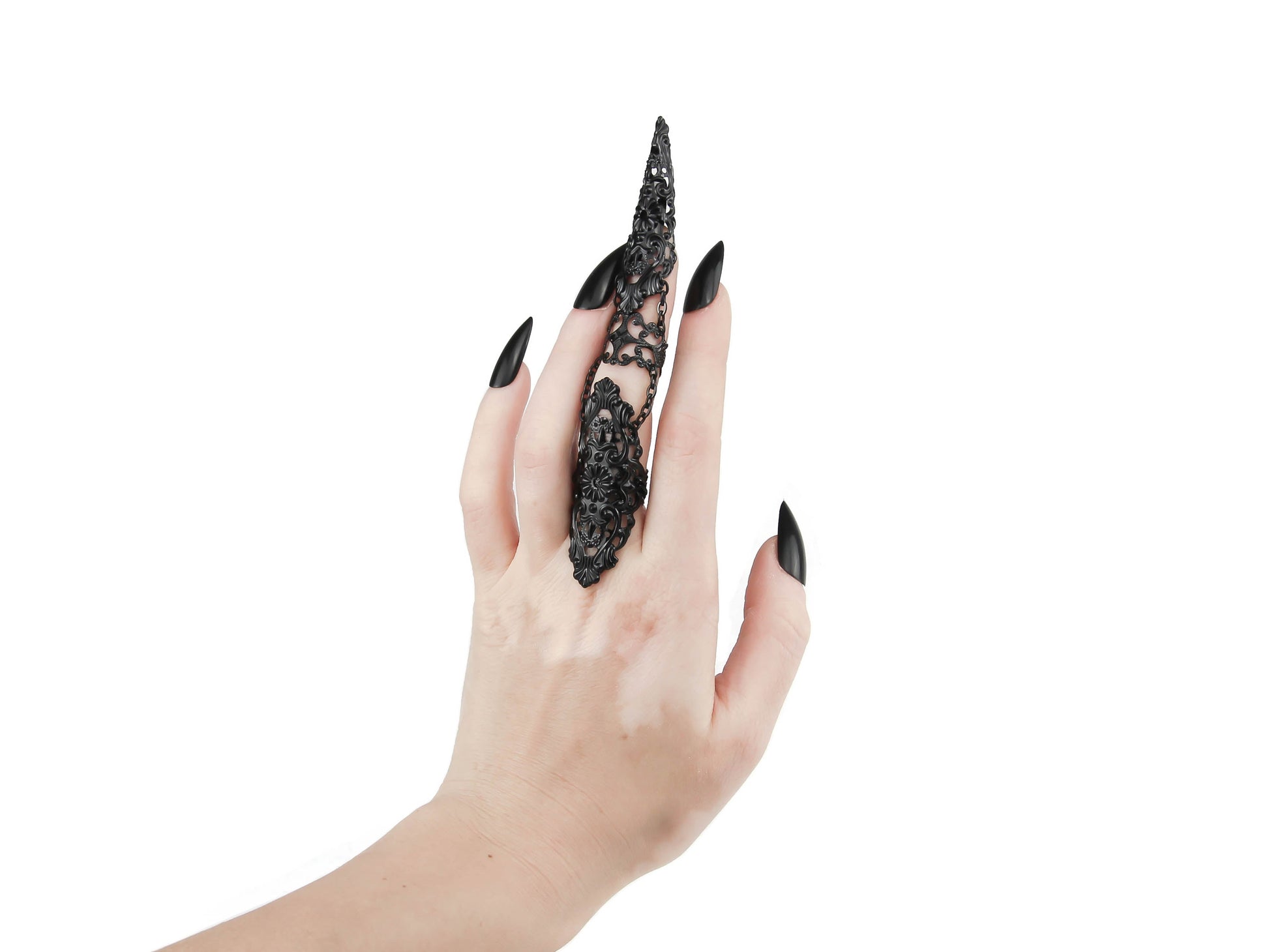 A hand models a stunning Myril Jewels full-finger ring on the middle finger, its black filigree design embodying the dark-avantgarde aesthetic. This handcrafted Italian jewelry piece, perfect for gothic and alternative style enthusiasts, makes a bold statement with its intricate details and elegant chain connection, set against a crisp white background