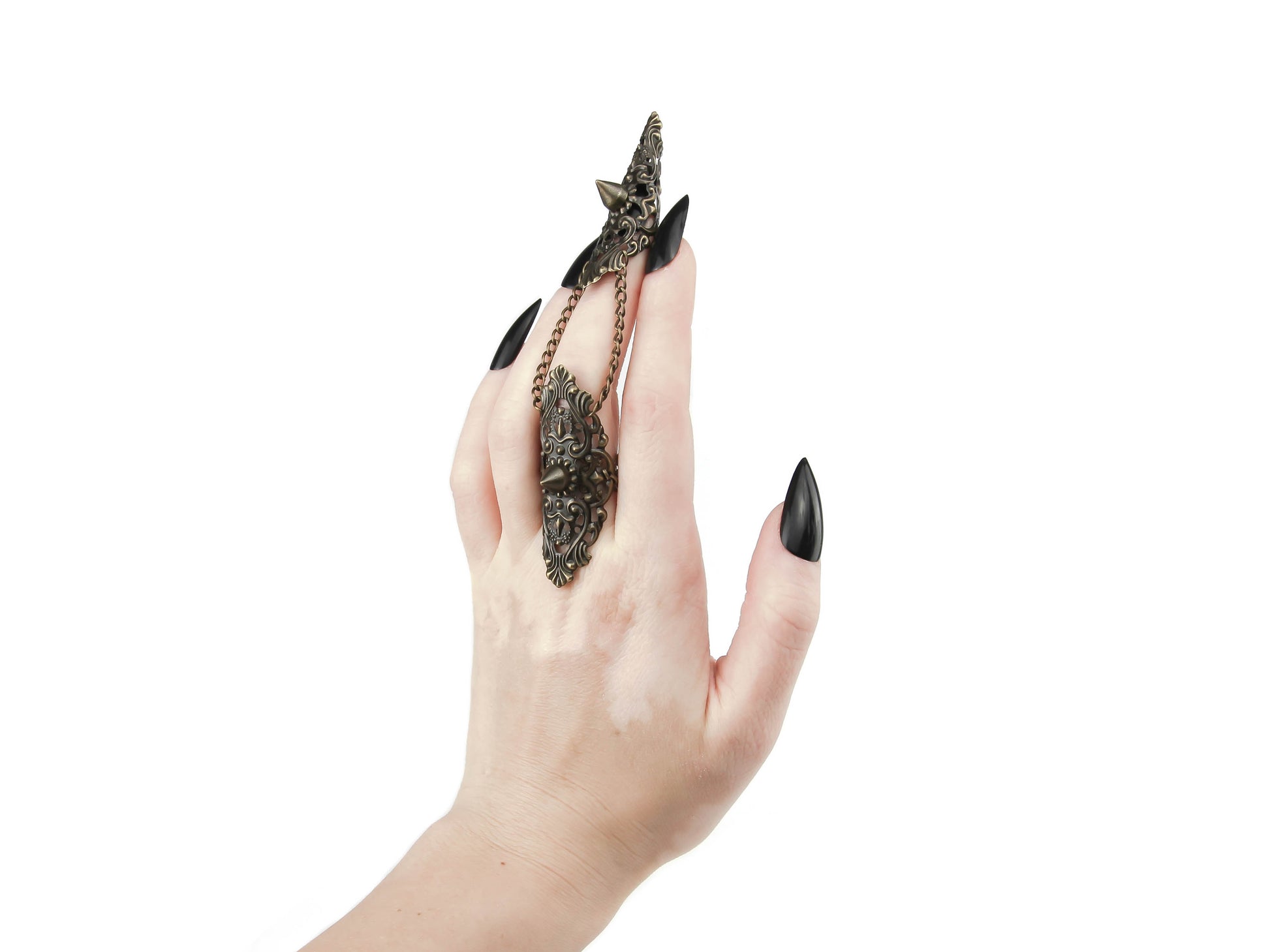 Enhance your gothic ensemble with Myril Jewels' studded claw ring in bronze, an exquisite piece of neo-goth jewelry. Worn on the middle finger, this ring features an intricate filigree design and is connected by a delicate chain to a matching band, creating a dramatic statement. Perfect for Halloween, punk style, or everyday wear, it captures the dark-avantgarde essence and is a must-have for gothic-chic, whimsigoth, or witchcore fashion lovers.