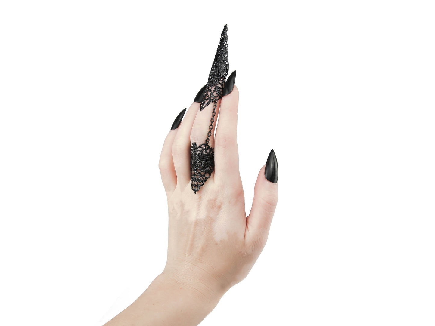 A hand is adorned with a Myril Jewels black full finger claw ring, crafted with exquisite filigree detailing. This luxurious neo-goth piece is a quintessential expression of dark-avantgarde jewelry, perfect for gothic, alternative, and drag queen aesthetics. The ring, suitable for Halloween, punk events, and everyday wear, also complements a whimsigoth or witchcore style and adds an edgy touch to rave party and festival outfits.