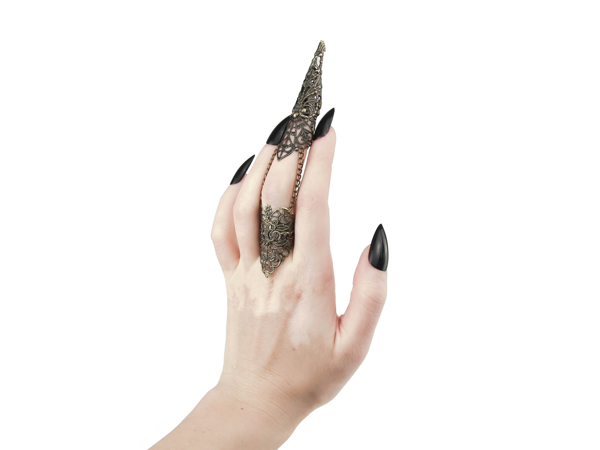 A hand is adorned with a Myril Jewels full finger claw ring, designed with a detailed filigree that evokes a neo-goth sensibility. The bronze claw ring extends over the length of the finger, culminating in a tapered tip, perfect for a dark-avantgarde look. This statement jewelry piece is ideal for Halloween, complements punk attire, and adds an edge to gothic-chic, whimsigoth, and witchcore styles. It's also suitable for everyday wear, rave parties, festival outfits, and drag queen adornments.