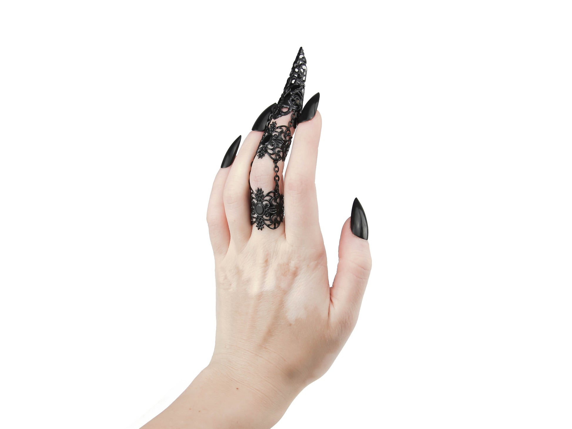 A hand model displays Myril Jewels' full finger black double ring, featuring a luxurious long black claw over the nail part. The claw ring's elaborate gold filigree design embodies the brand's neo-goth style, making it a striking choice for gothic and alternative fashion enthusiasts. It's a versatile piece that fits seamlessly into a collection of Halloween jewelry, adds an edge to everyday minimal goth attire, and serves as a statement piece for rave party jewelry or festival jewels.