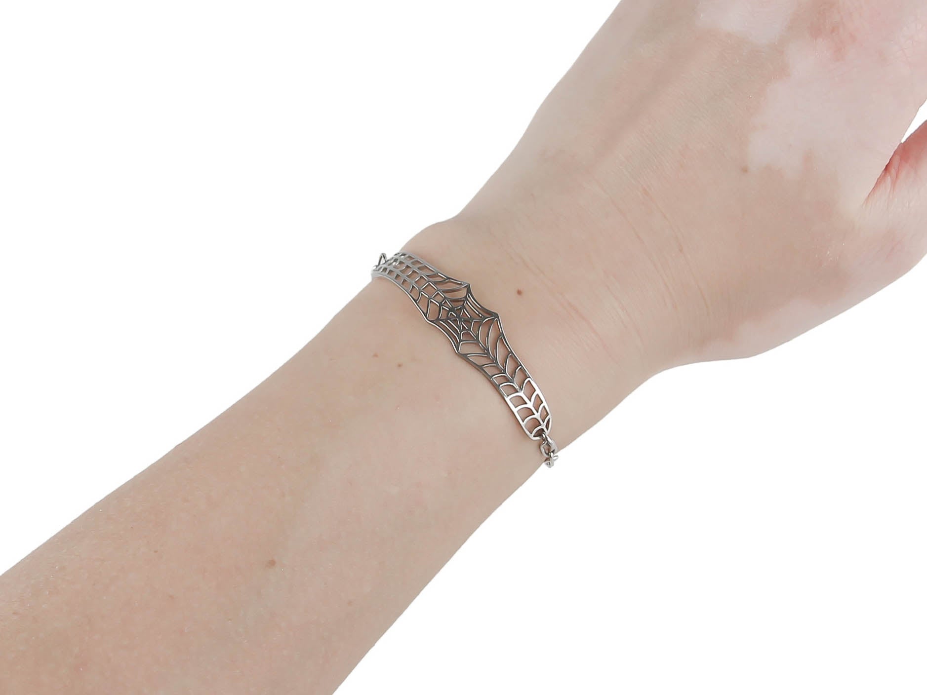 A Myril Jewels chain bracelet with a distinctive spiderweb design elegantly graces the hand, showcasing a luxurious dark-avantgarde aesthetic. This spider-inspired jewel reflects a neo-goth charm. This piece is a perfect fit for Halloween jewelry enthusiasts or for adding a gothic-chic touch to everyday wear. It also appeals to fans of whimsigoth and witchcore, seamlessly fitting into a minimal goth lifestyle or as an accessory for rave party and festival outfits.