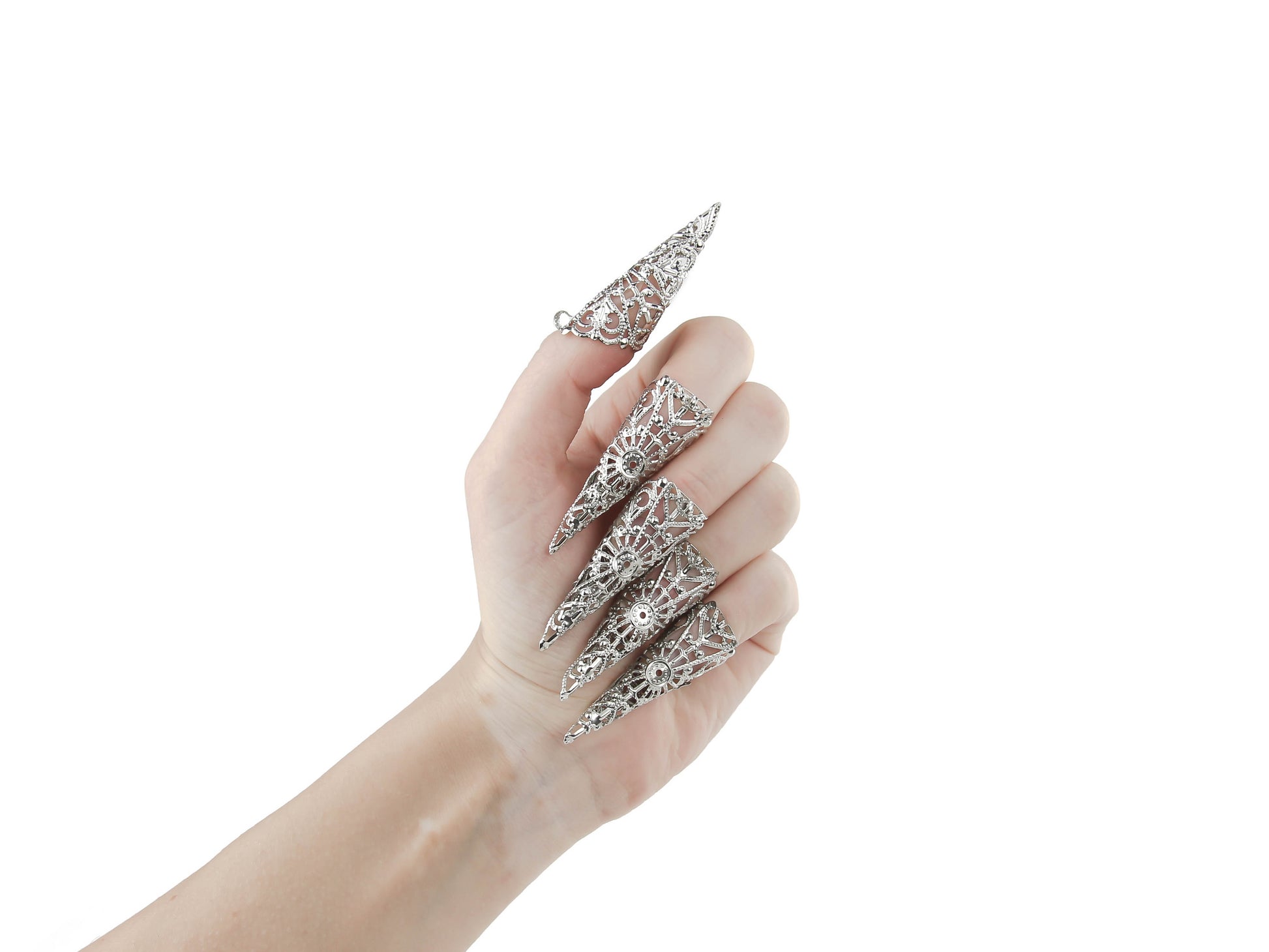 A hand models a full set of Myril Jewels nail claw jewelry, each piece detailed with an ornate silver filigree design that captures the brand’s signature neo-goth style. These claws are perfect for those seeking dark-avantgarde accessories, making a dramatic statement for Halloween, embodying the gothic-chic and whimsigoth aesthetic. They are also ideal for adding an edge to everyday minimal goth looks or for complementing witchcore outfits at rave parties and festivals.