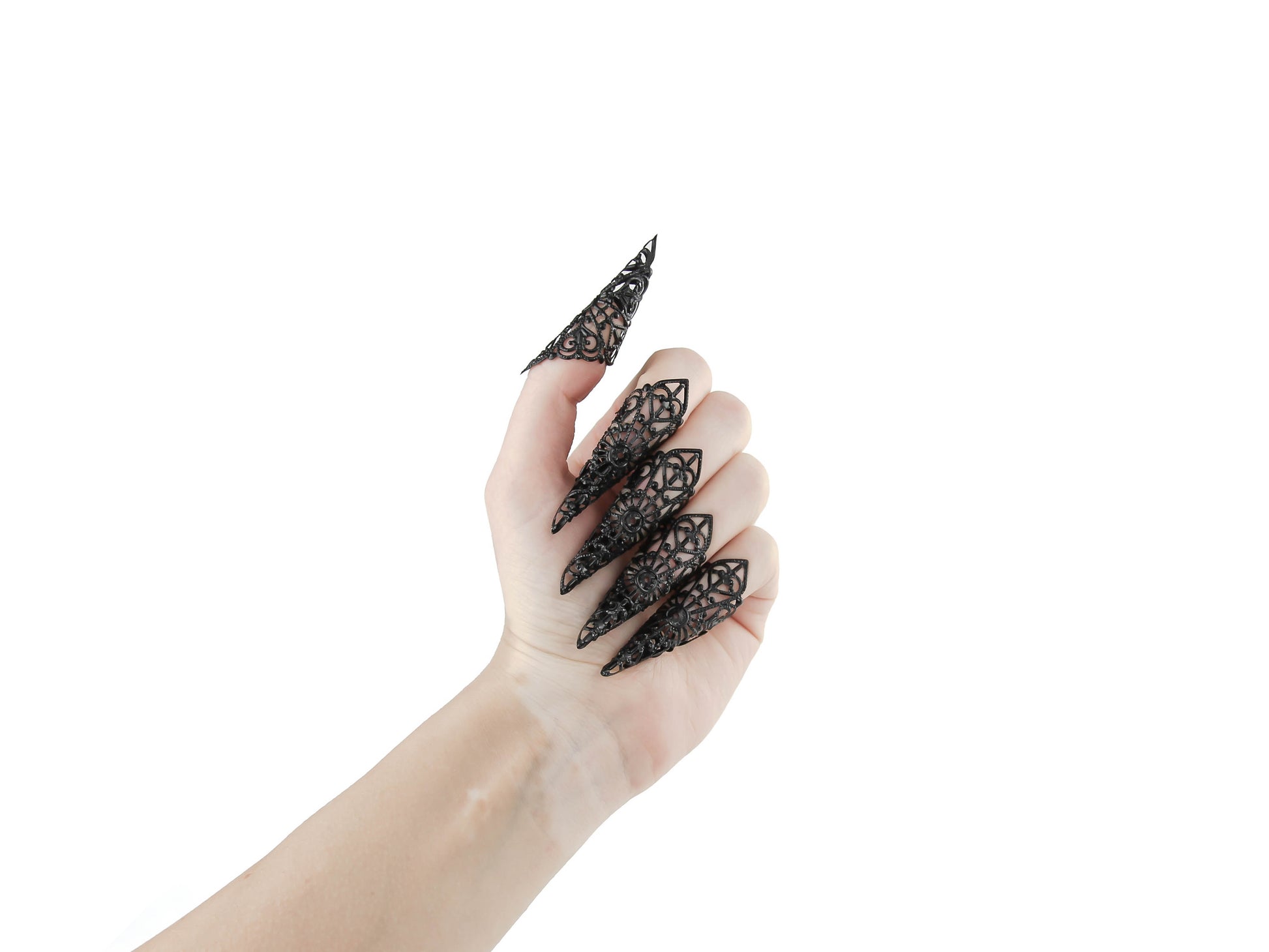 A hand is adorned with a full set of Myril Jewels black nail claw jewelry, each piece featuring elaborate filigree work that epitomizes the neo-goth aesthetic. These claws present a dark-avantgarde twist suitable for gothic, witchcore, and whimsigoth styles. Perfect for Halloween, they also add an edgy, gothic-chic element to everyday wear and are a bold accessory choice for rave parties and festival attire