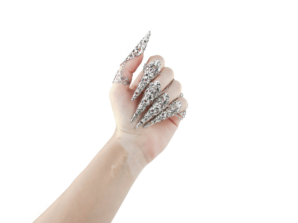 An almost closed hand models Myril Jewels' full set of armored claw rings, embodying the brand's unique dark-avantgarde aesthetic. Designed for gothic and alternative fashion lovers, the intricate silver filigree work on each piece adds a touch of Neo Gothic flair, perfect for Halloween, Punk, or Gothic-chic styles. These rings are a daring choice for Witchcore enthusiasts or anyone looking to add a dramatic edge to their everyday wear