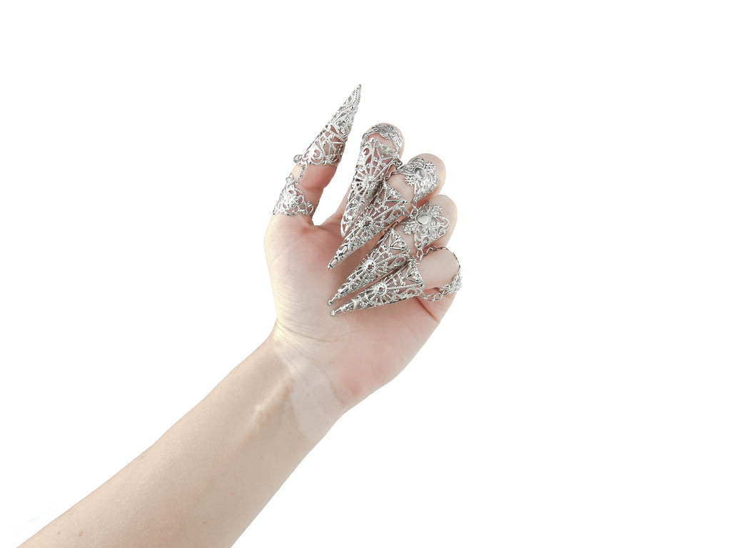 Adorn your hand with the Myril Jewels full hand set of midi rings, designed with an edgy claw-like silhouette for a neo-gothic statement. Perfect for gothic and alternative styles, these intricate silver rings are ideal for Halloween, adding a punk touch to your wardrobe. Their elaborate design captures the essence of gothic-chic jewellery, making them a staple for whimsigoth and witchcore aesthetics. Whether it's everyday wear or as a bold highlight for rave parties and festivals