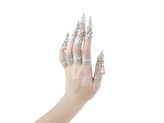 A hand is dramatically enhanced with a full set of Myril Jewels silver claw rings, each finger adorned with an elaborate filigree design that embodies the essence of neo-goth fashion. This dark-avantgarde accessory set is perfect for gothic, witchcore, and whimsigoth enthusiasts, making a bold statement for Halloween, everyday wear, or as captivating rave party and festival jewels.