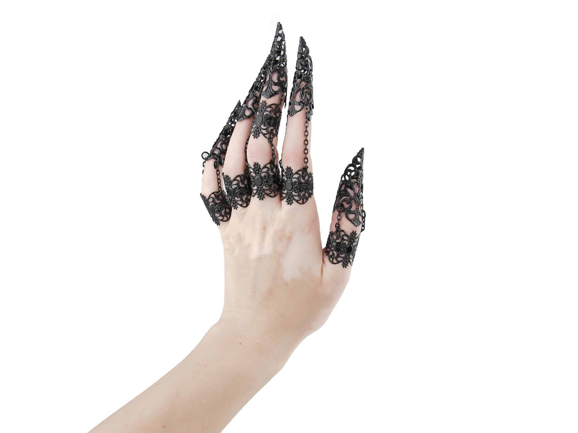 A hand is elegantly adorned with a full set of Myril Jewels claw rings, each finger crowned with an intricate, black lace-like filigree design that evokes the neo-goth spirit. This dark-avantgarde accessory is a perfect embodiment of gothic-chic, ideal for adding a dramatic flair to Halloween attire or as a standout addition to any minimal goth, whimsigoth, or witchcore ensemble. These claw rings are not only a bold statement for rave parties and festivals but also add an edge to everyday wear.