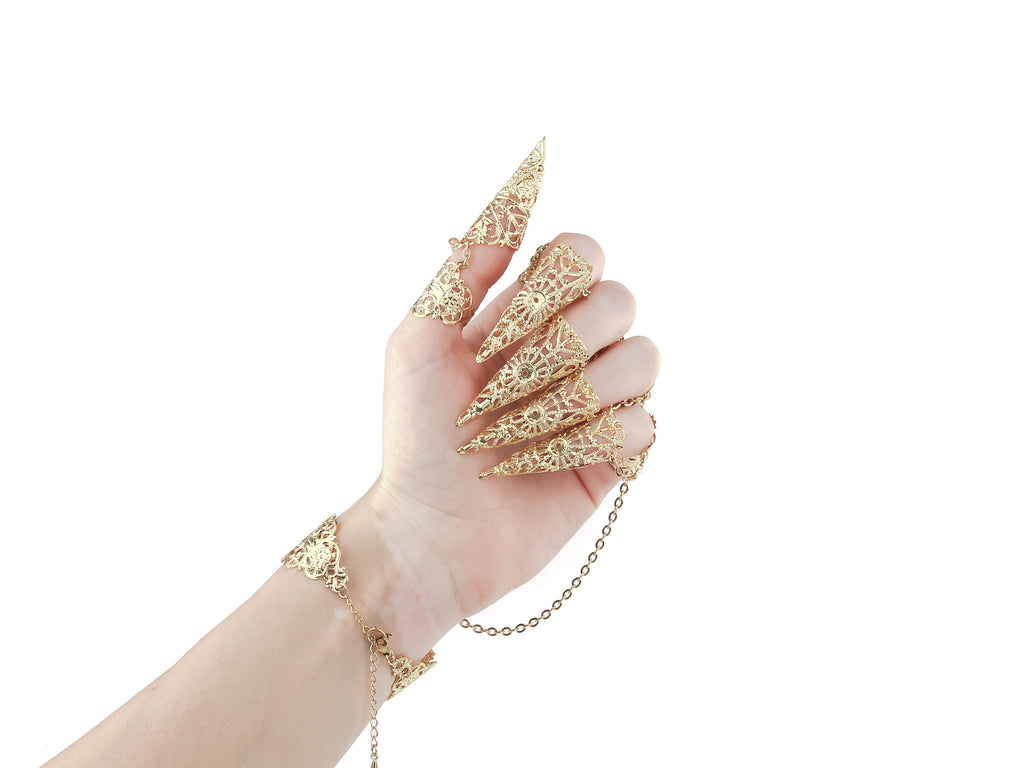 Elegant hand showcasing ornate gold jewelry with extended claw design, connected by delicate chains to the bracelet, embodying a bold gothic and witchy aesthetic ideal for statement accessorizing.