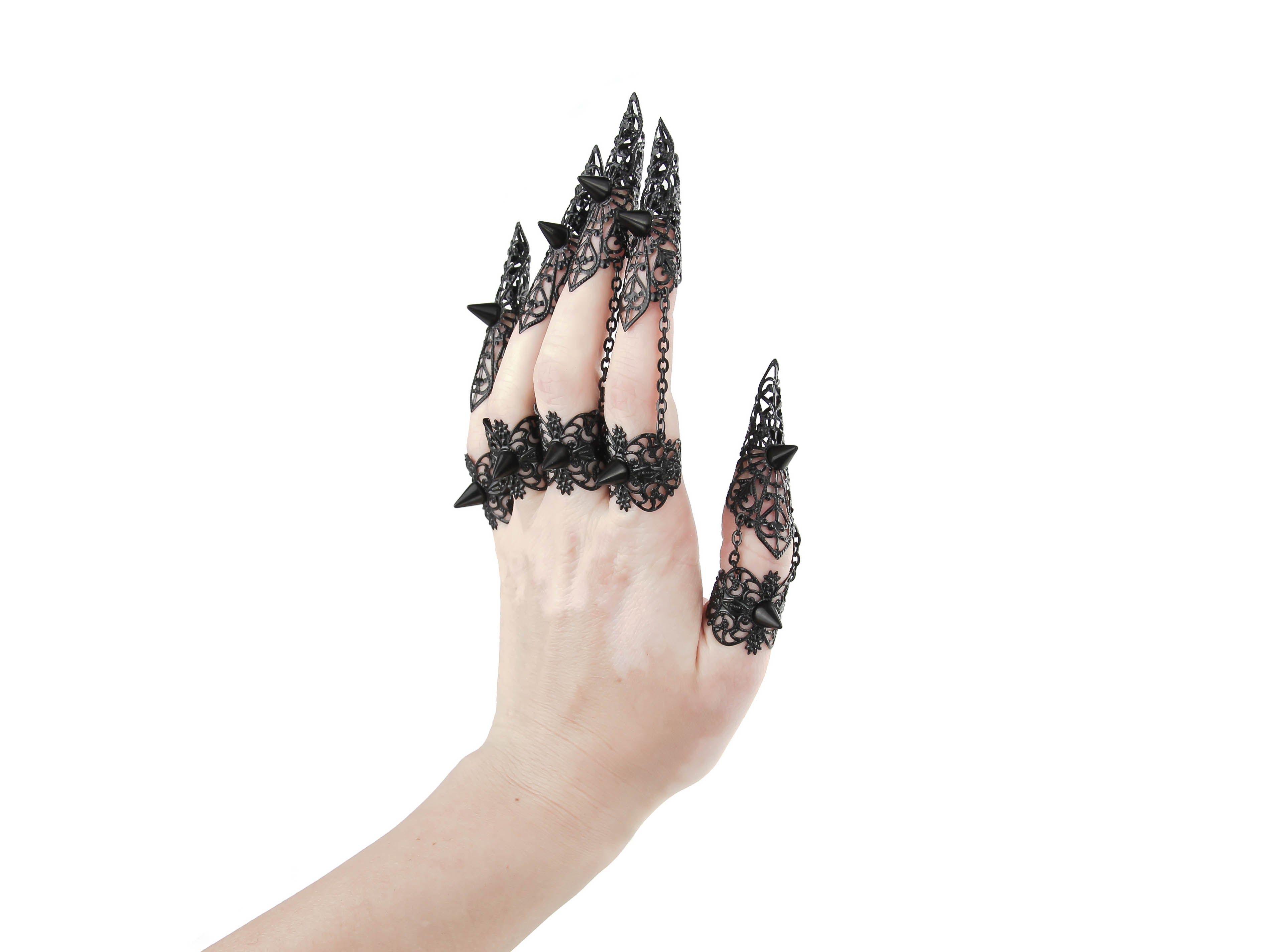 A set of black claw rings with studs adorns a hand, exemplifying the dark-avantgarde style of Myril Jewels. These bold, neo-gothic pieces are a fit for Halloween, adding a punk edge to gothic-chic looks, perfect for the fashion-forward goth girlfriend or as a daring festival jewel.